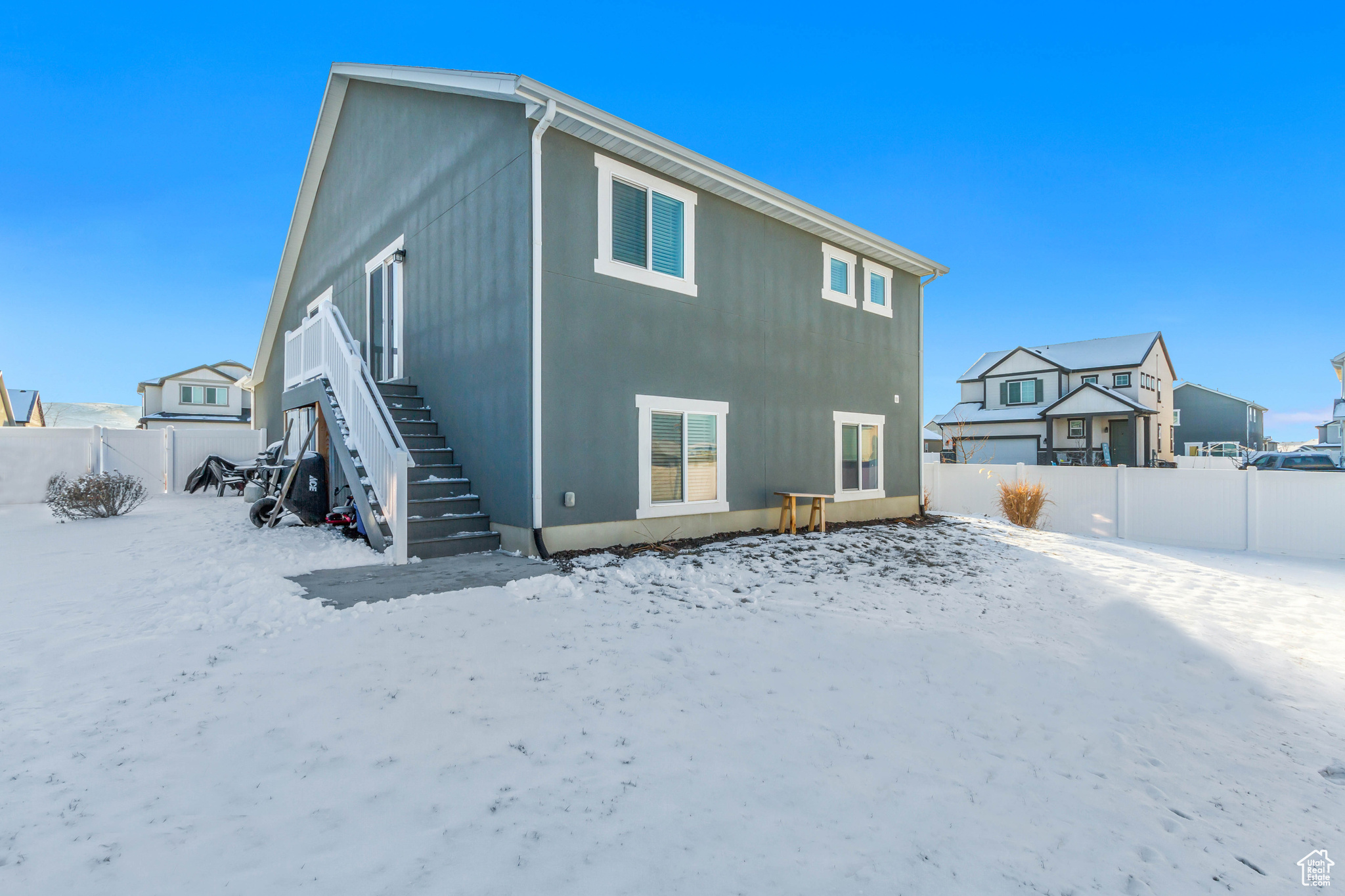 Snow covered house featuring fence and a residential view