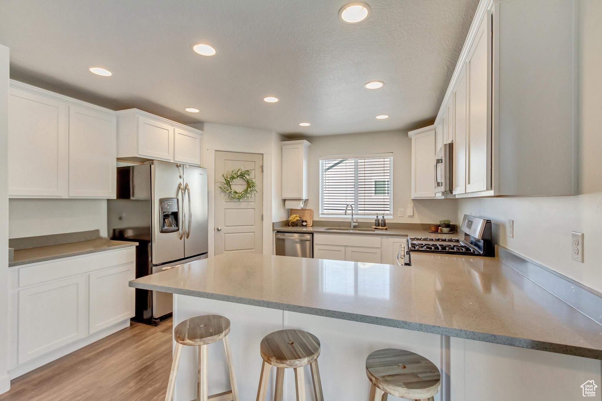 Kitchen with a peninsula, appliances with stainless steel finishes, a breakfast bar area, and white cabinets