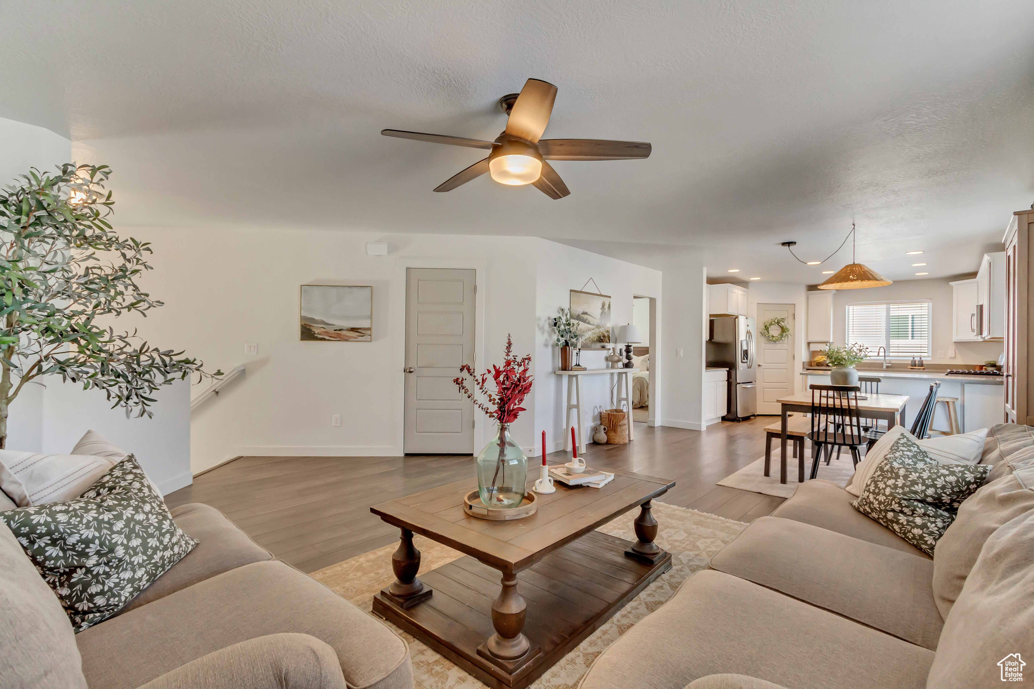 Living area with light wood-type flooring, a textured ceiling, baseboards, and a ceiling fan