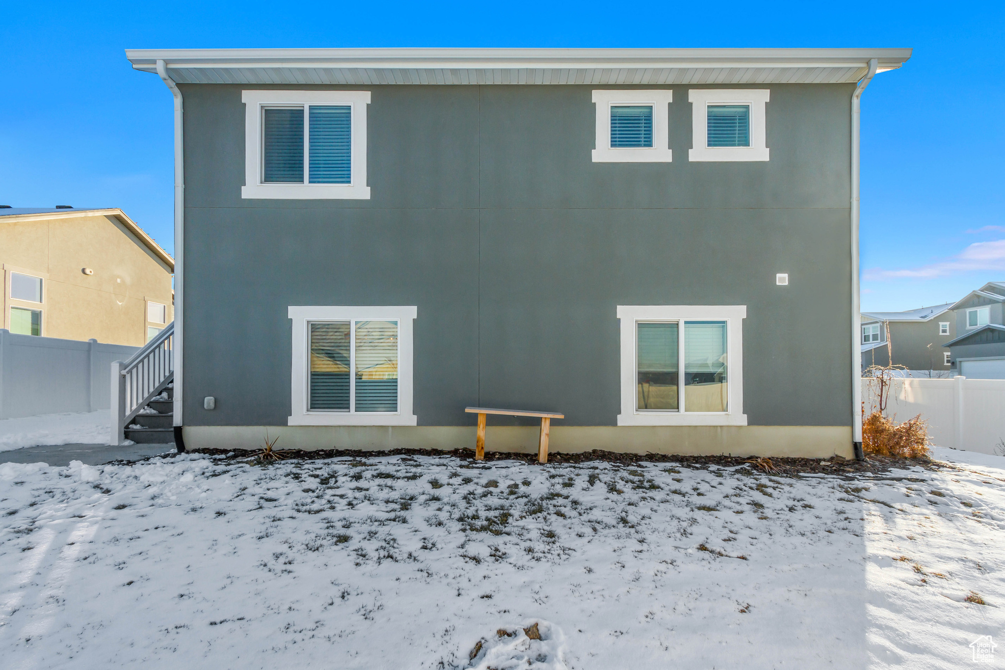 Snow covered rear of property with fence and stucco siding
