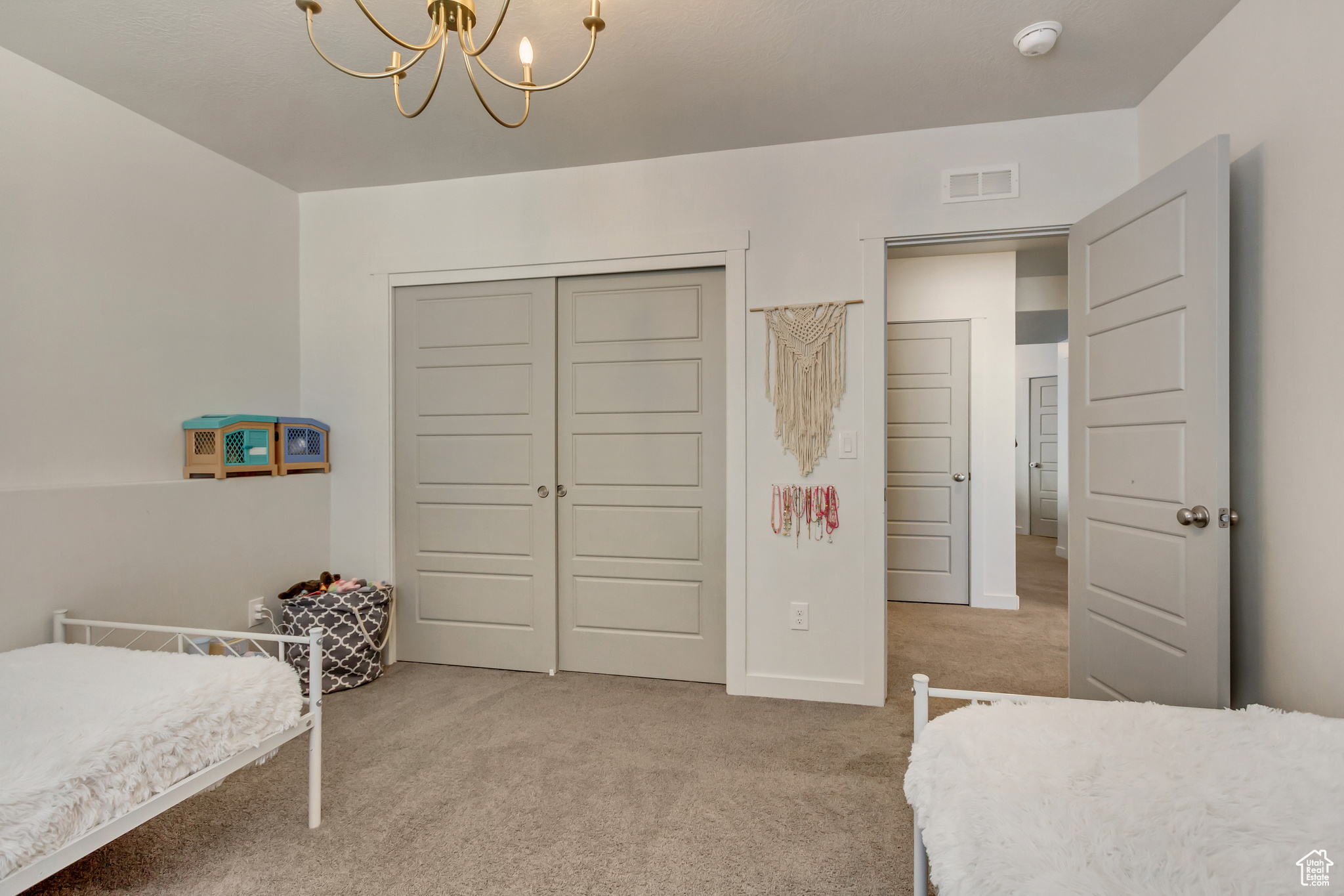 Bedroom with light carpet, a closet, visible vents, and an inviting chandelier