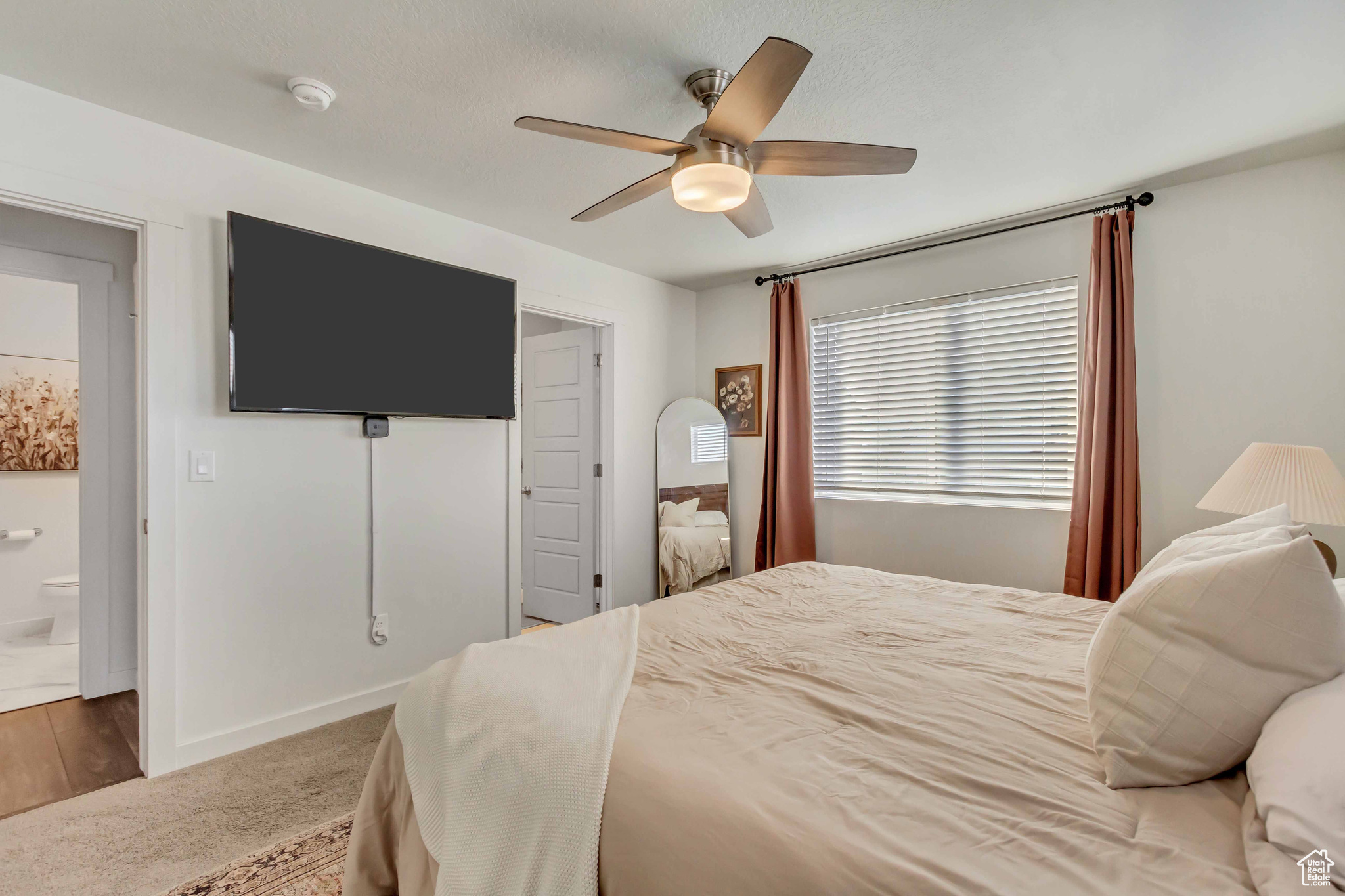 Bedroom featuring carpet floors, ensuite bath, baseboards, and a ceiling fan