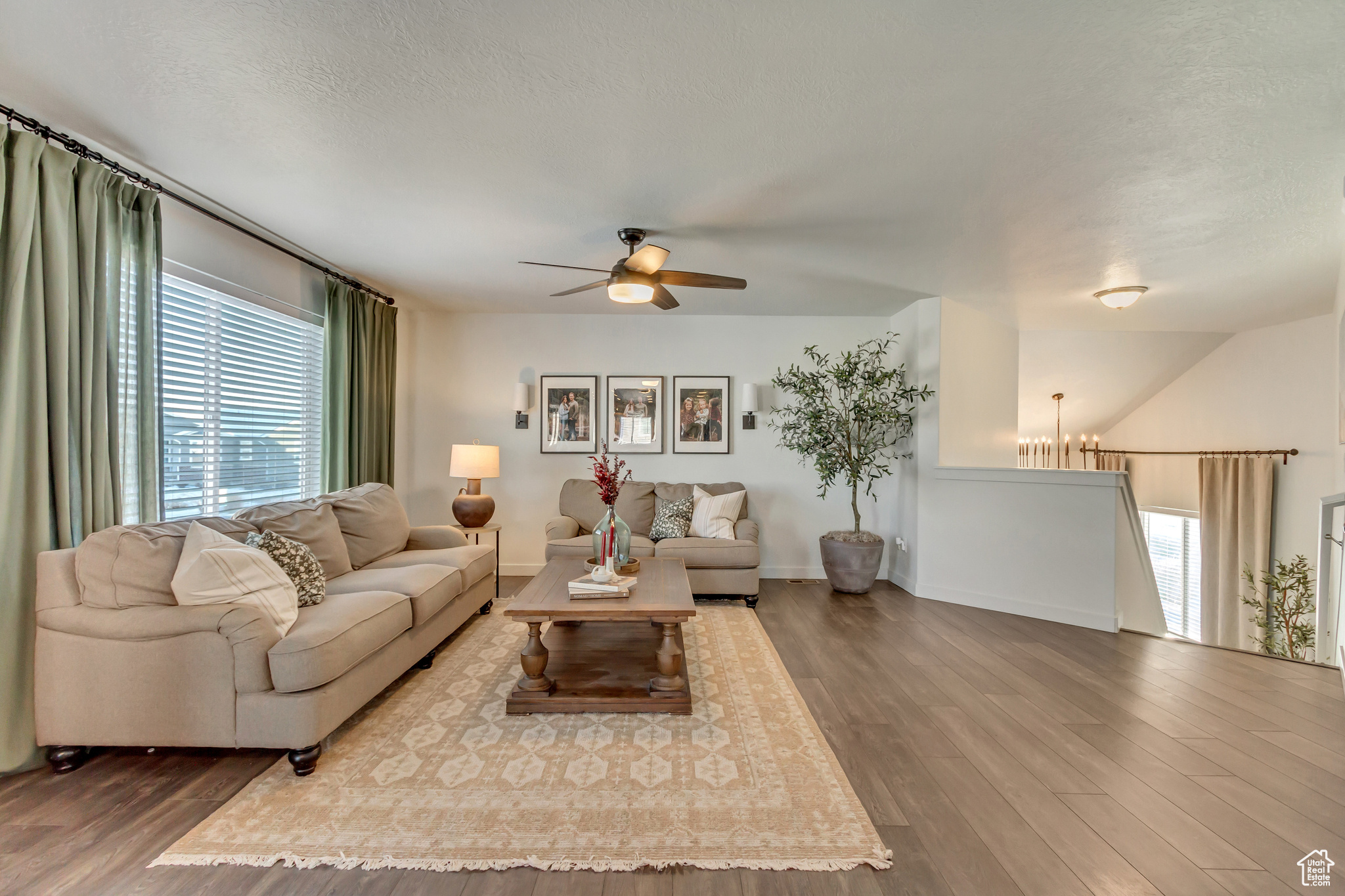 Living area with a textured ceiling, ceiling fan with notable chandelier, wood finished floors, and baseboards
