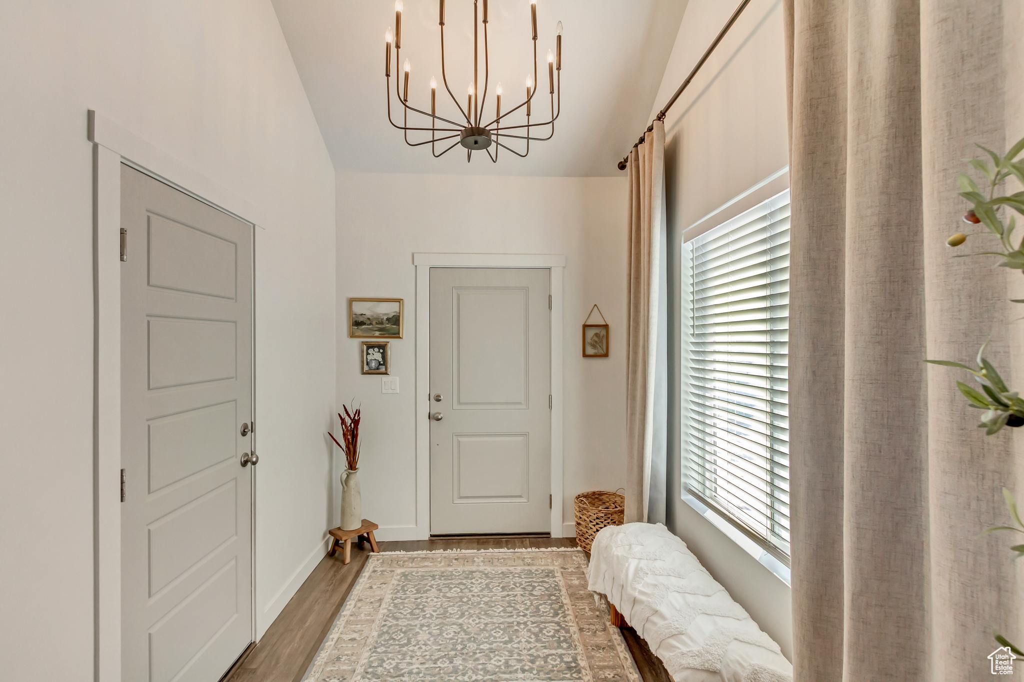 Doorway featuring an inviting chandelier, baseboards, and wood finished floors
