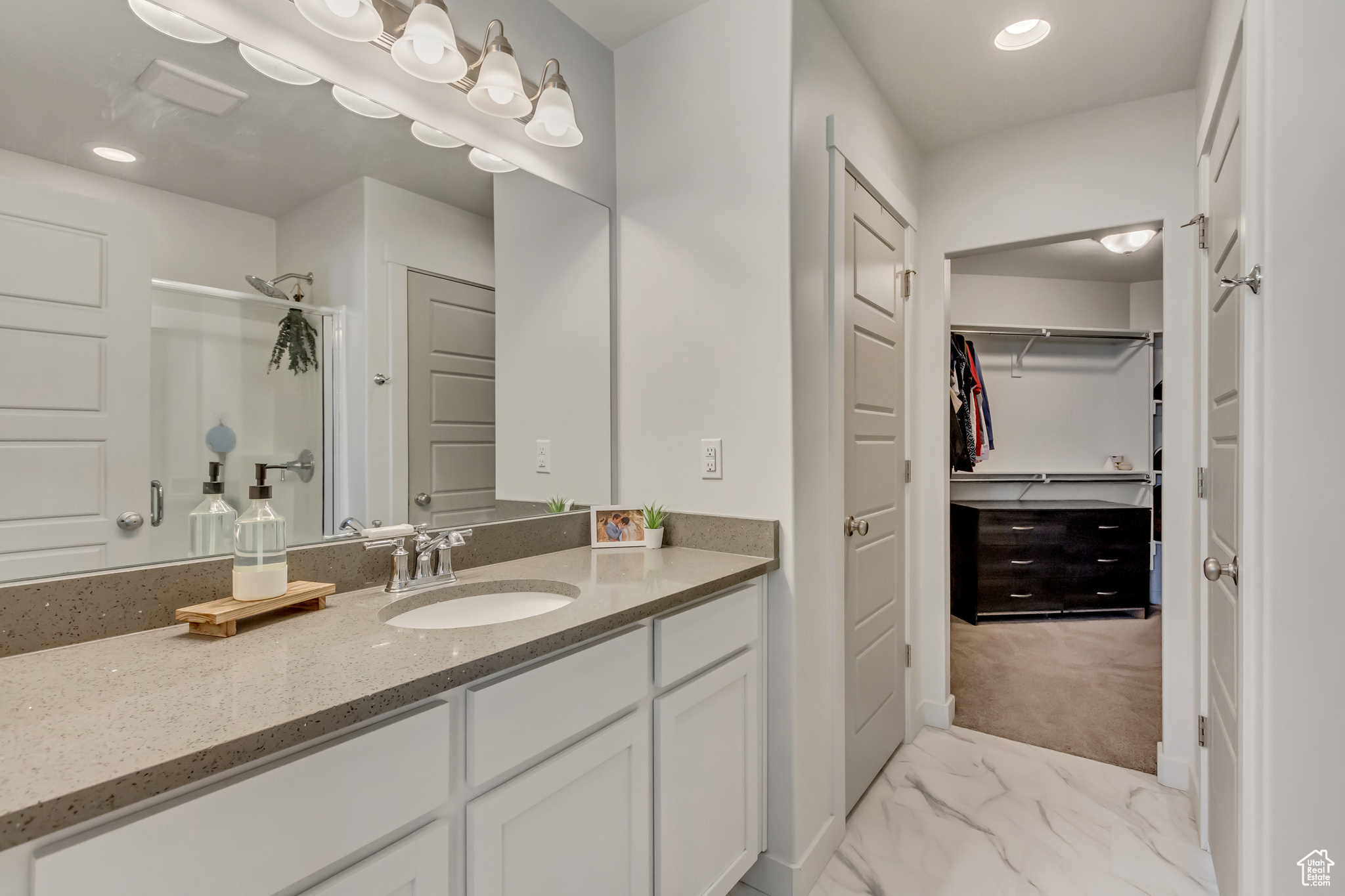 Bathroom featuring a stall shower, marble finish floor, a spacious closet, vanity, and recessed lighting