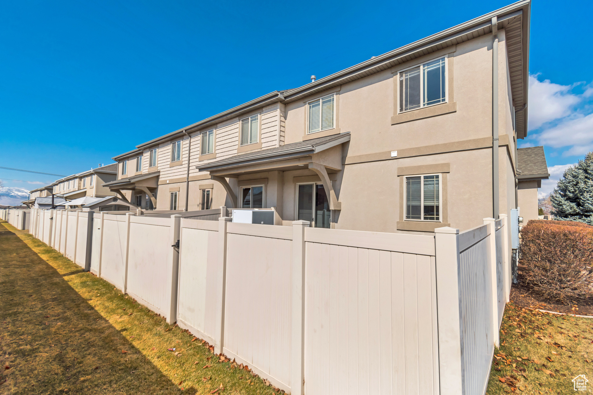 Rear view of property with a yard, fence, and stucco siding