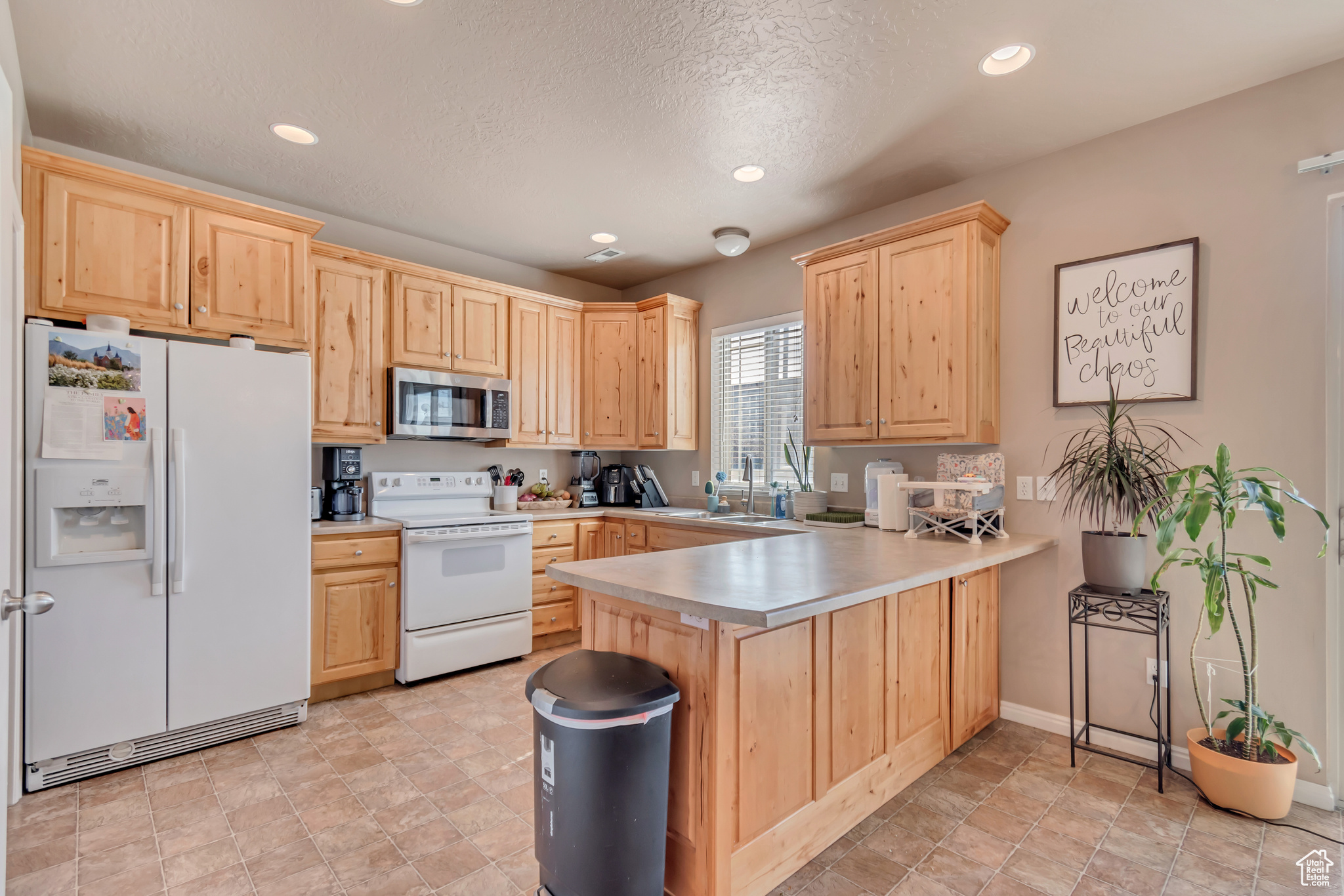 Kitchen with light brown cabinetry, light countertops, recessed lighting, a peninsula, and appliances