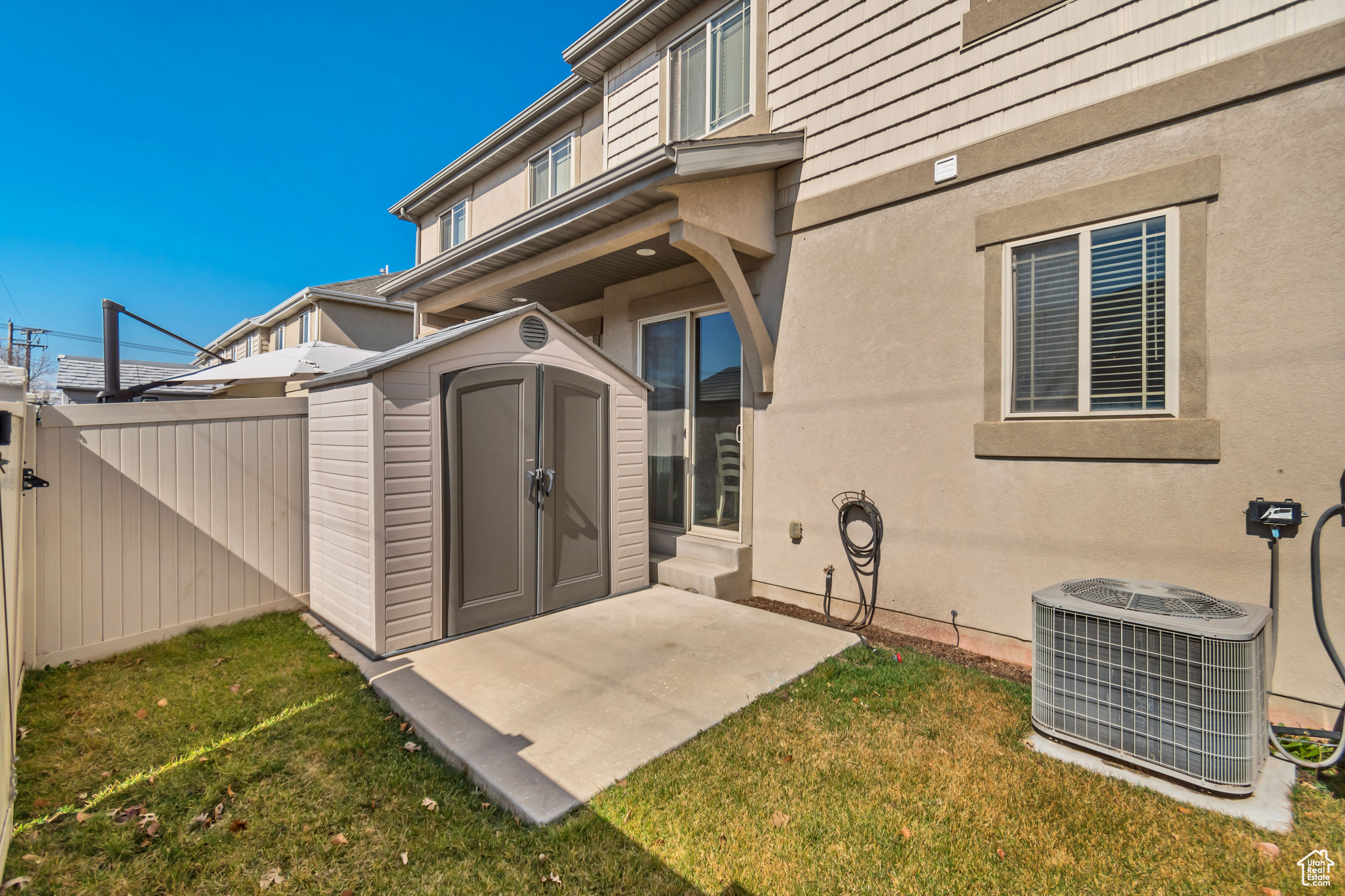 Rear view of house featuring fence, a shed, central AC unit, and stucco siding
