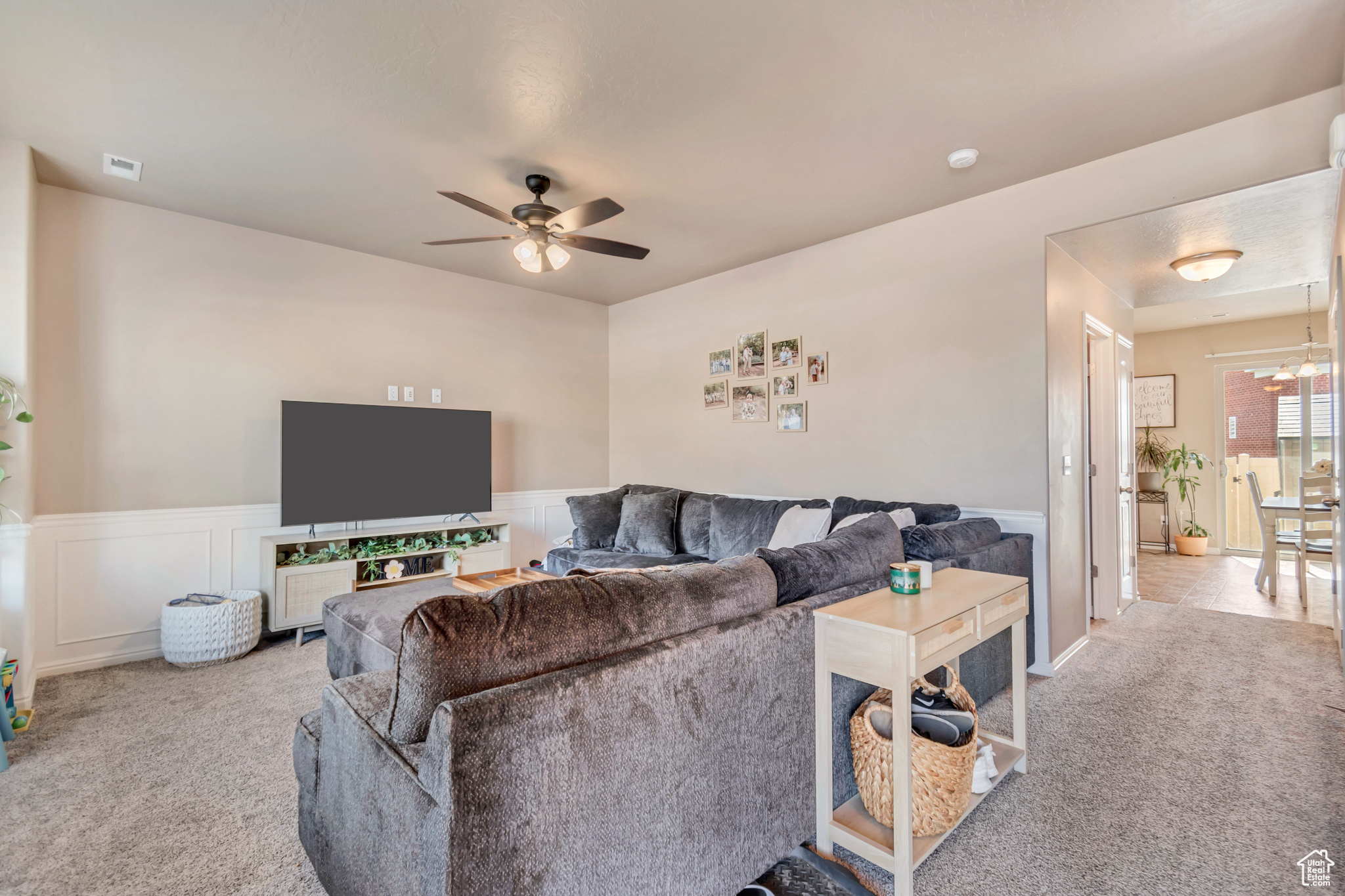 Living area with visible vents, wainscoting, ceiling fan, and carpet floors