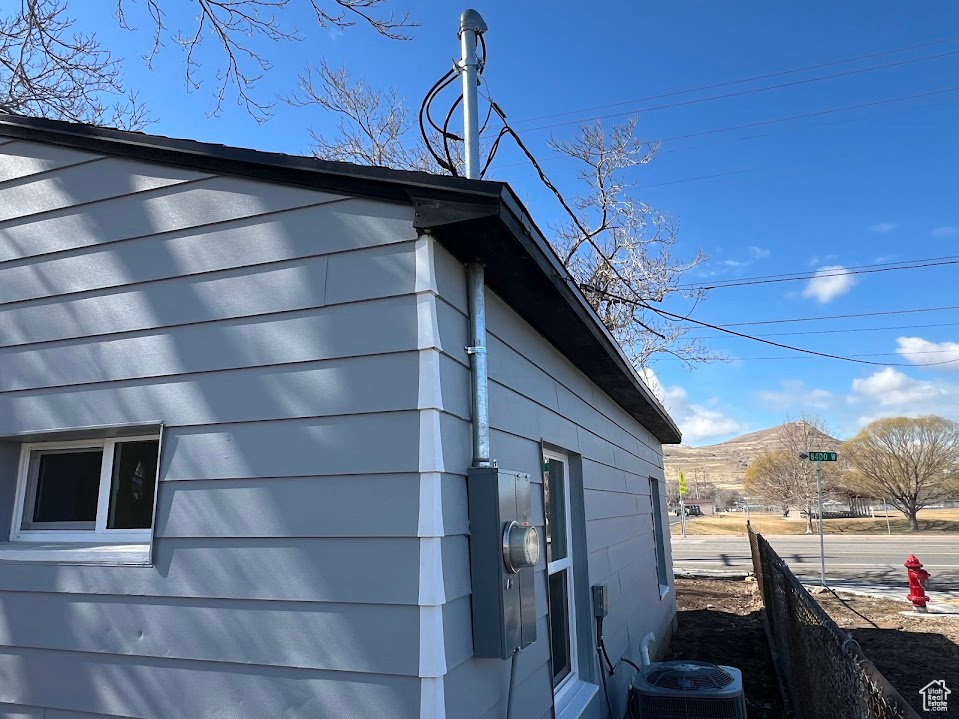 View of side of home with a mountain view and central AC unit