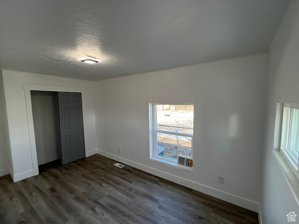 Unfurnished bedroom with a closet, dark wood finished floors, a textured ceiling, and baseboards