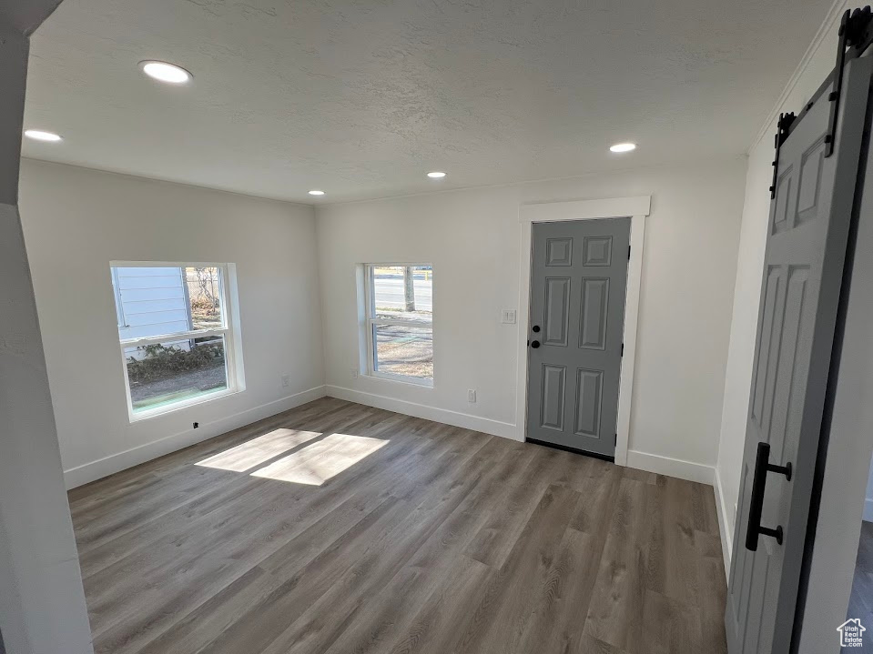 Entryway with recessed lighting, wood finished floors, baseboards, and a barn door