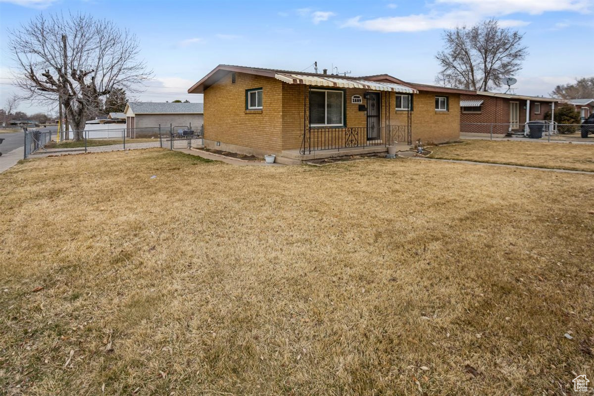 View of front facade with brick siding, a front yard, and fence