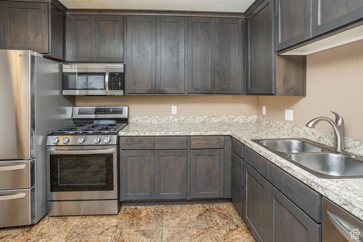 Kitchen featuring appliances with stainless steel finishes, a sink, and dark brown cabinetry