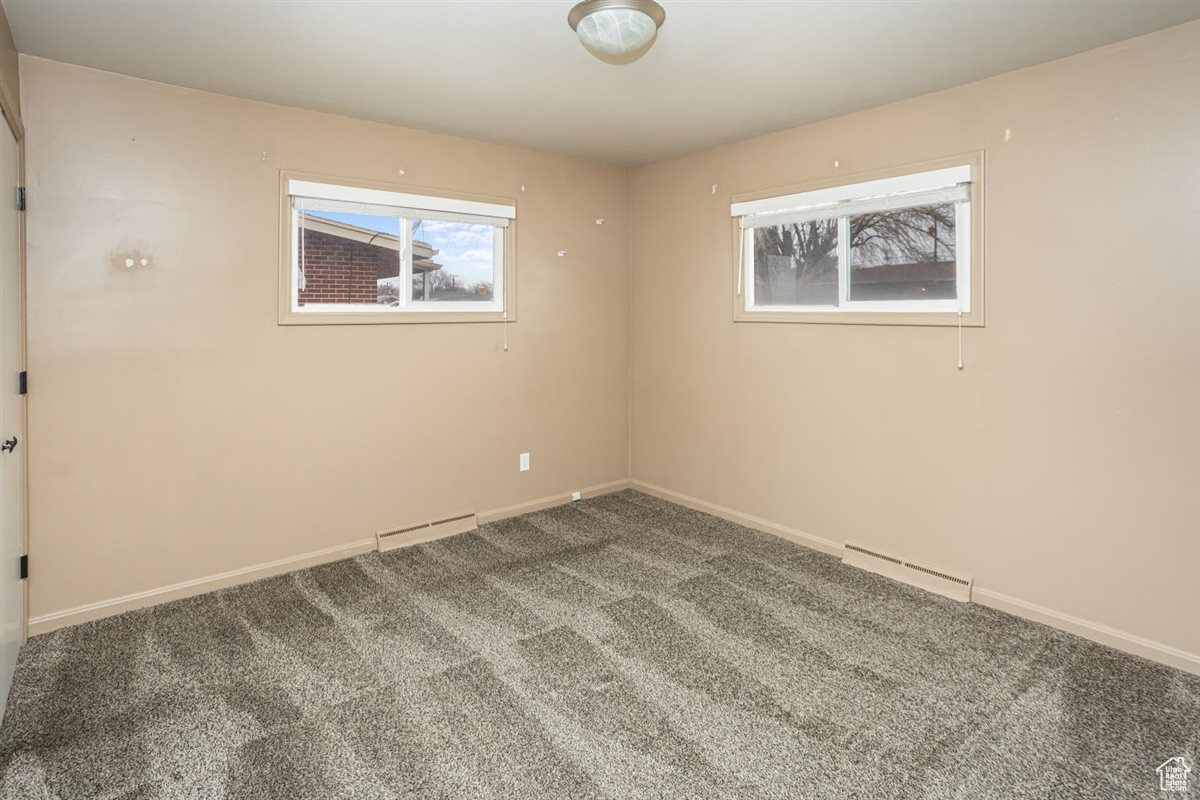 Empty room featuring baseboards, visible vents, baseboard heating, and carpet flooring