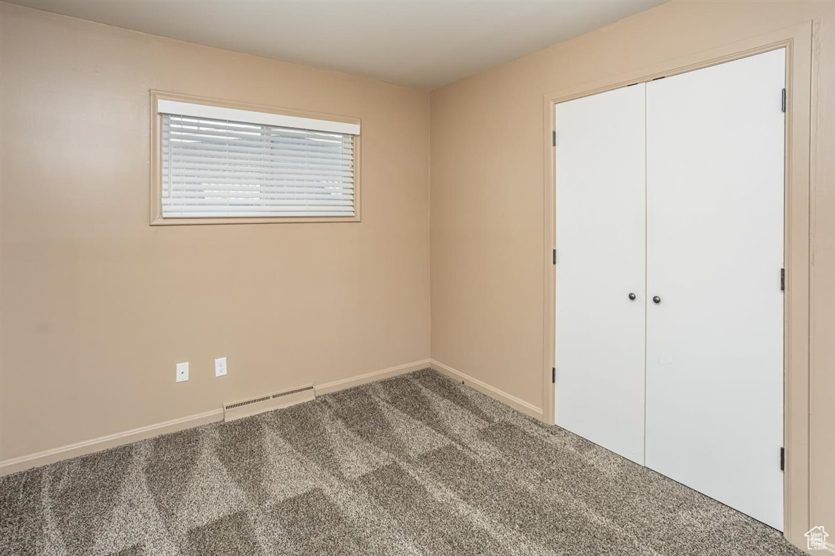 Unfurnished bedroom featuring carpet, a closet, visible vents, baseboard heating, and baseboards