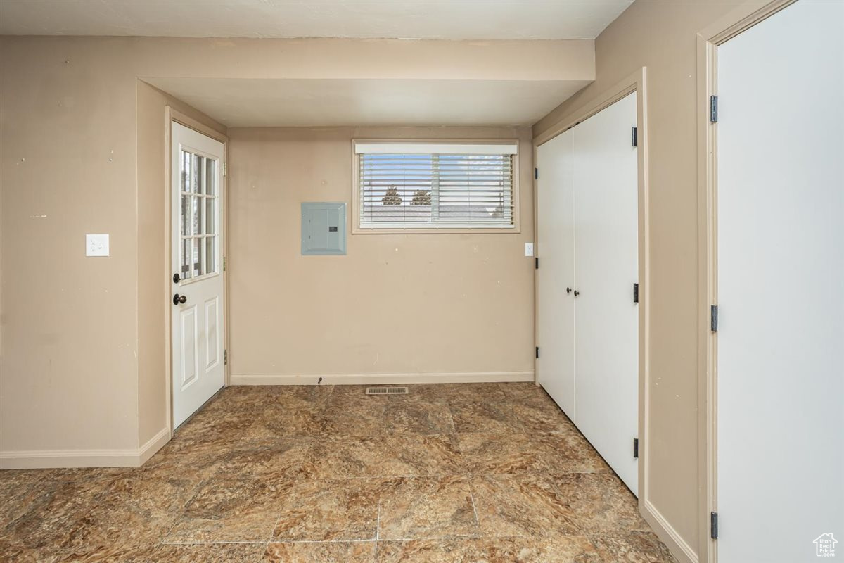 Interior space featuring stone finish flooring, electric panel, and baseboards