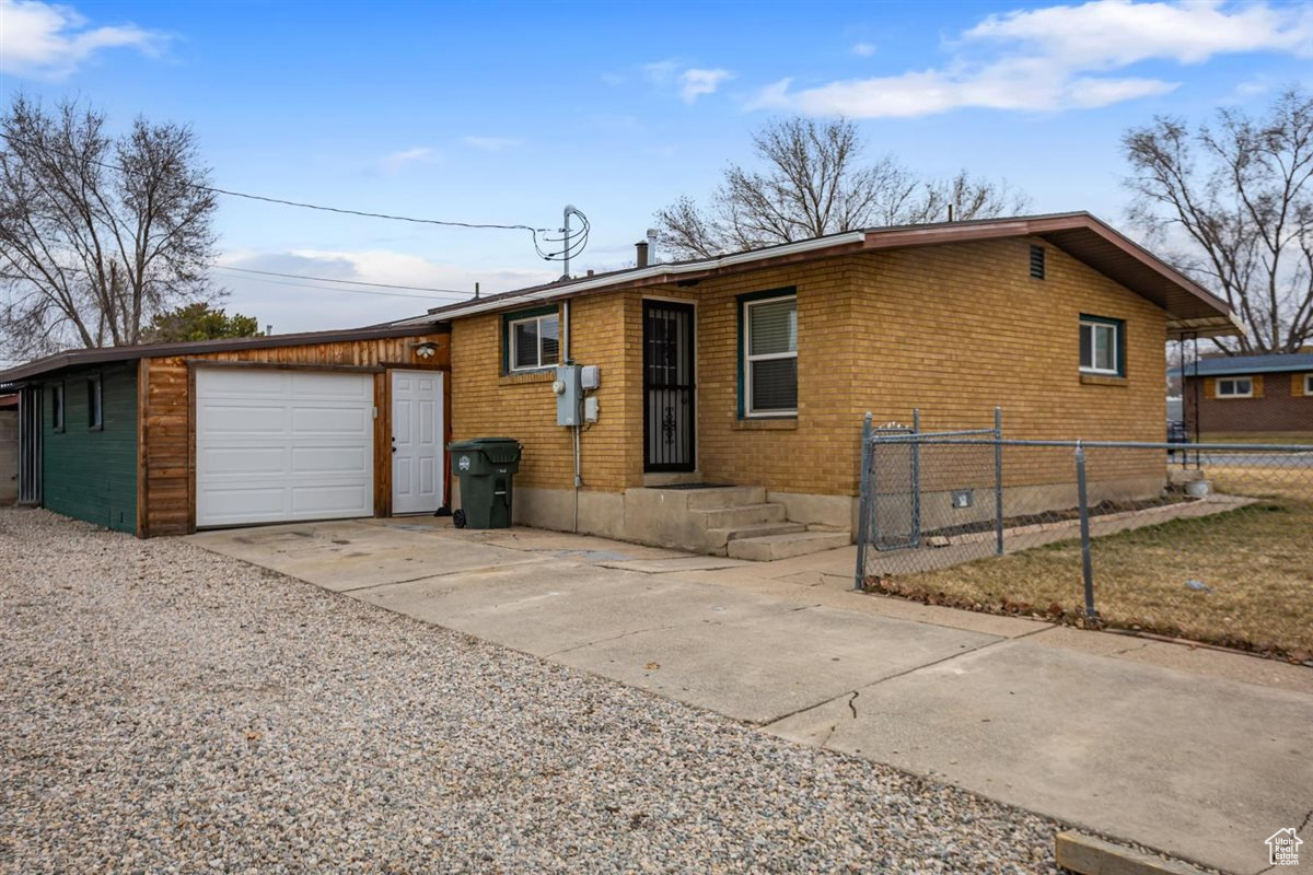 Ranch-style home featuring concrete driveway, brick siding, fence, and an attached garage