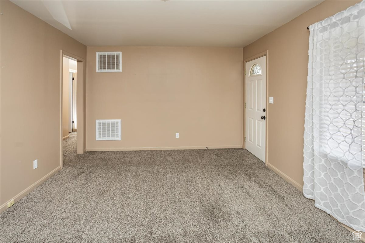 Carpeted empty room with visible vents and baseboards