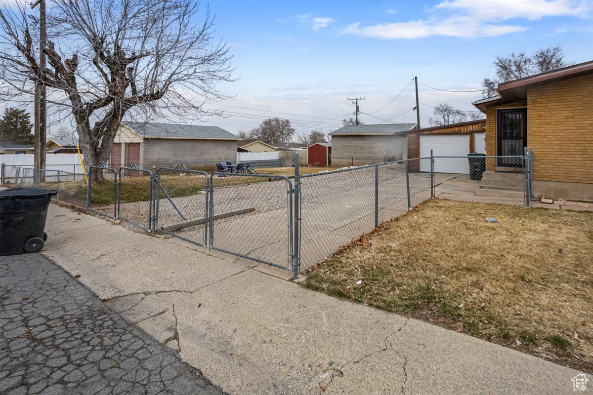 Exterior space featuring a garage, a gate, fence, and an outdoor structure