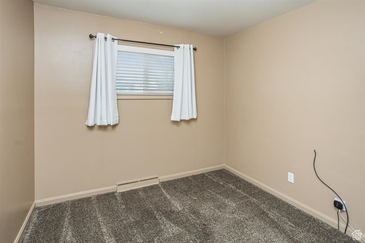 Carpeted empty room featuring a baseboard radiator and baseboards