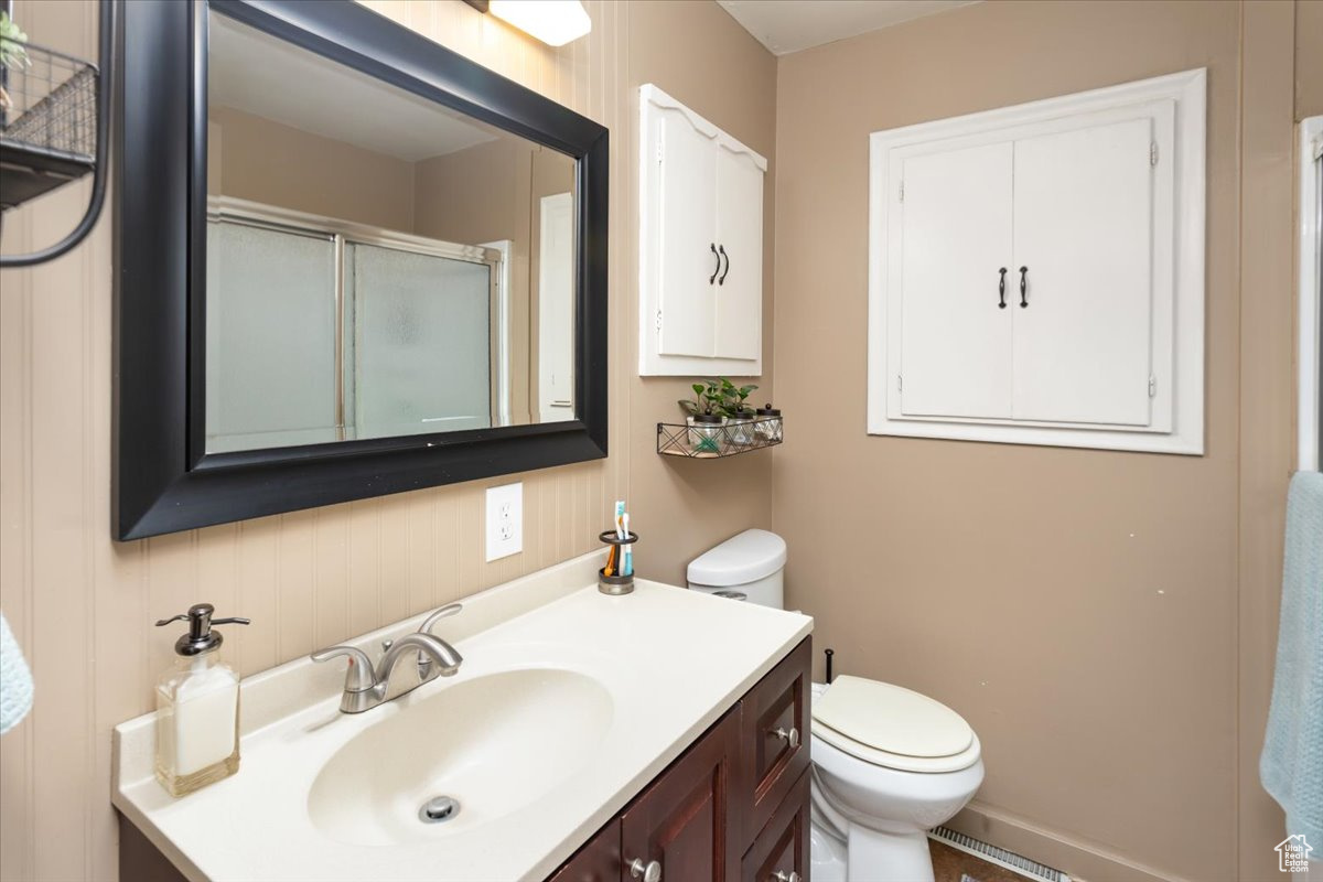 Bathroom with vanity, a shower with door, and toilet