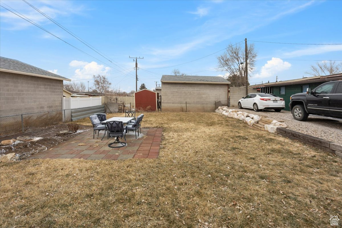 View of yard with a storage unit and a patio