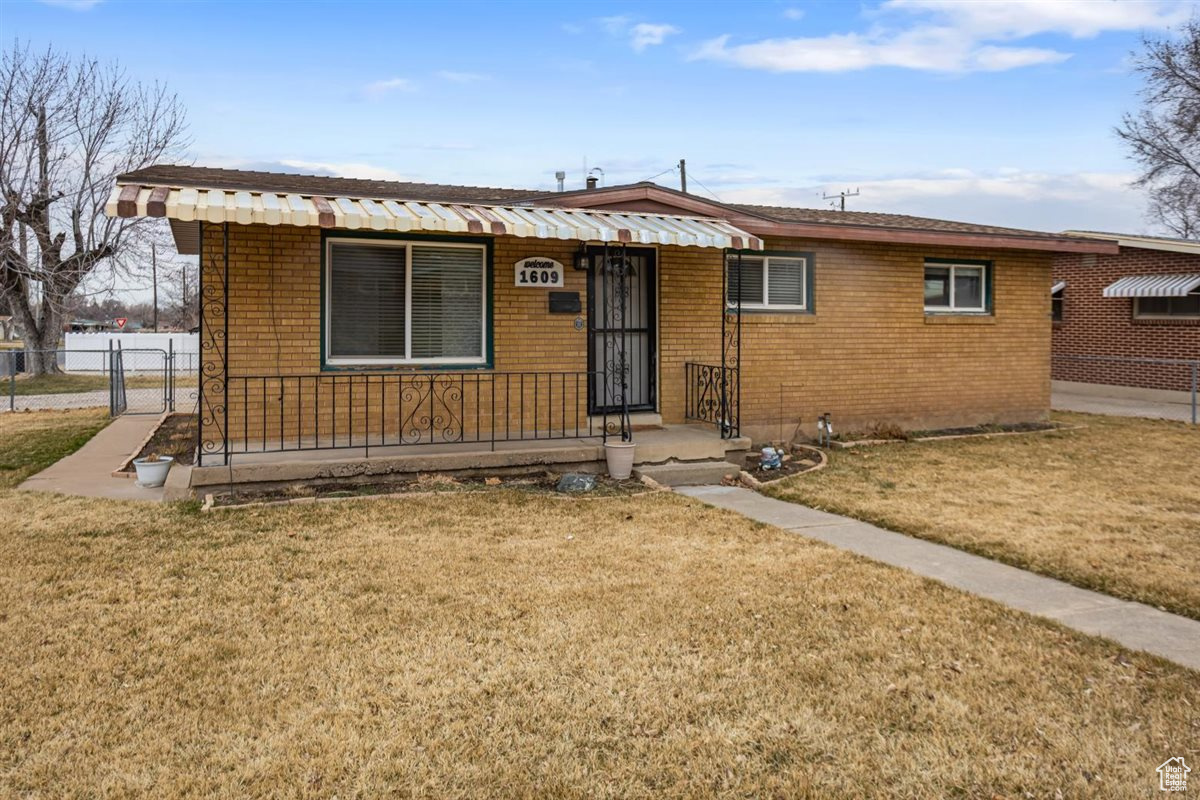 View of front of house featuring a gate, fence, a front lawn, and brick siding