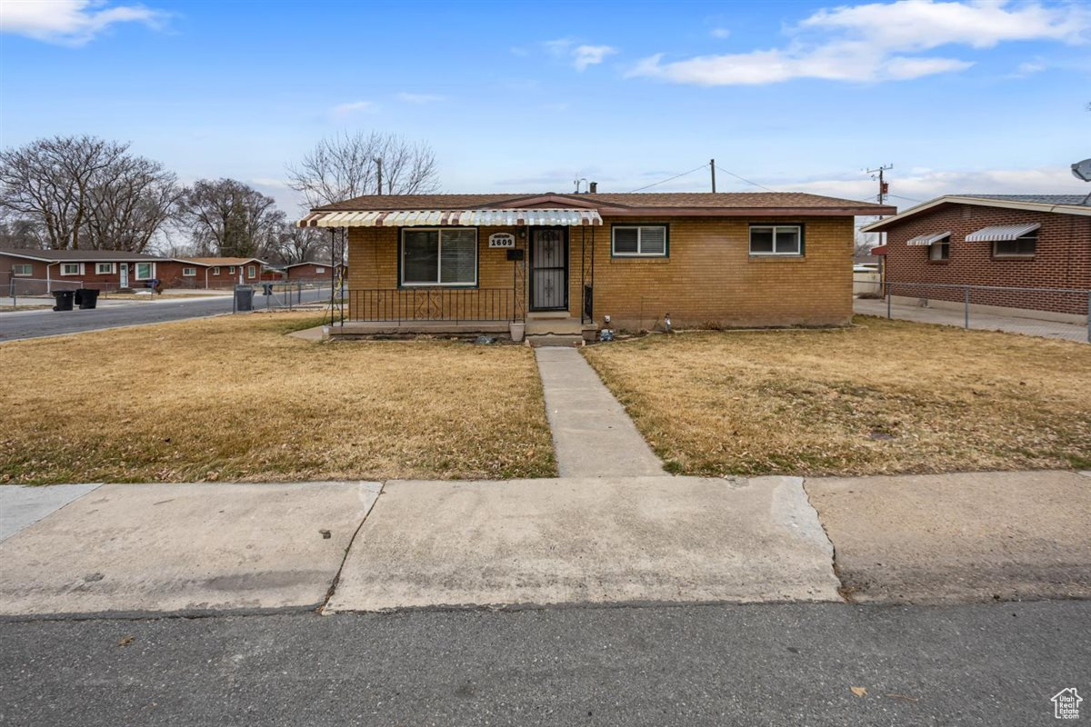 View of front of home featuring brick siding, fence, and a front yard