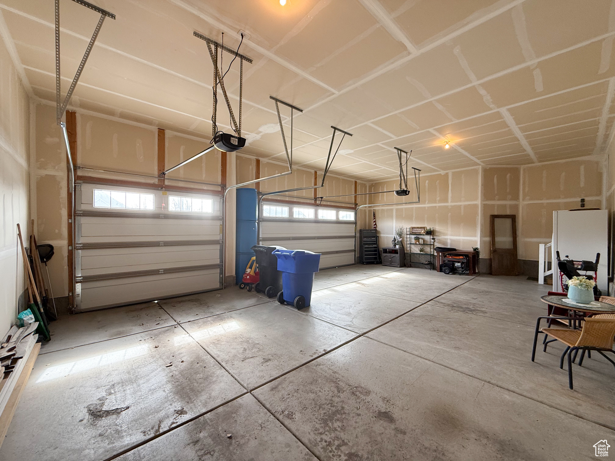 Garage featuring a garage door opener and freestanding refrigerator