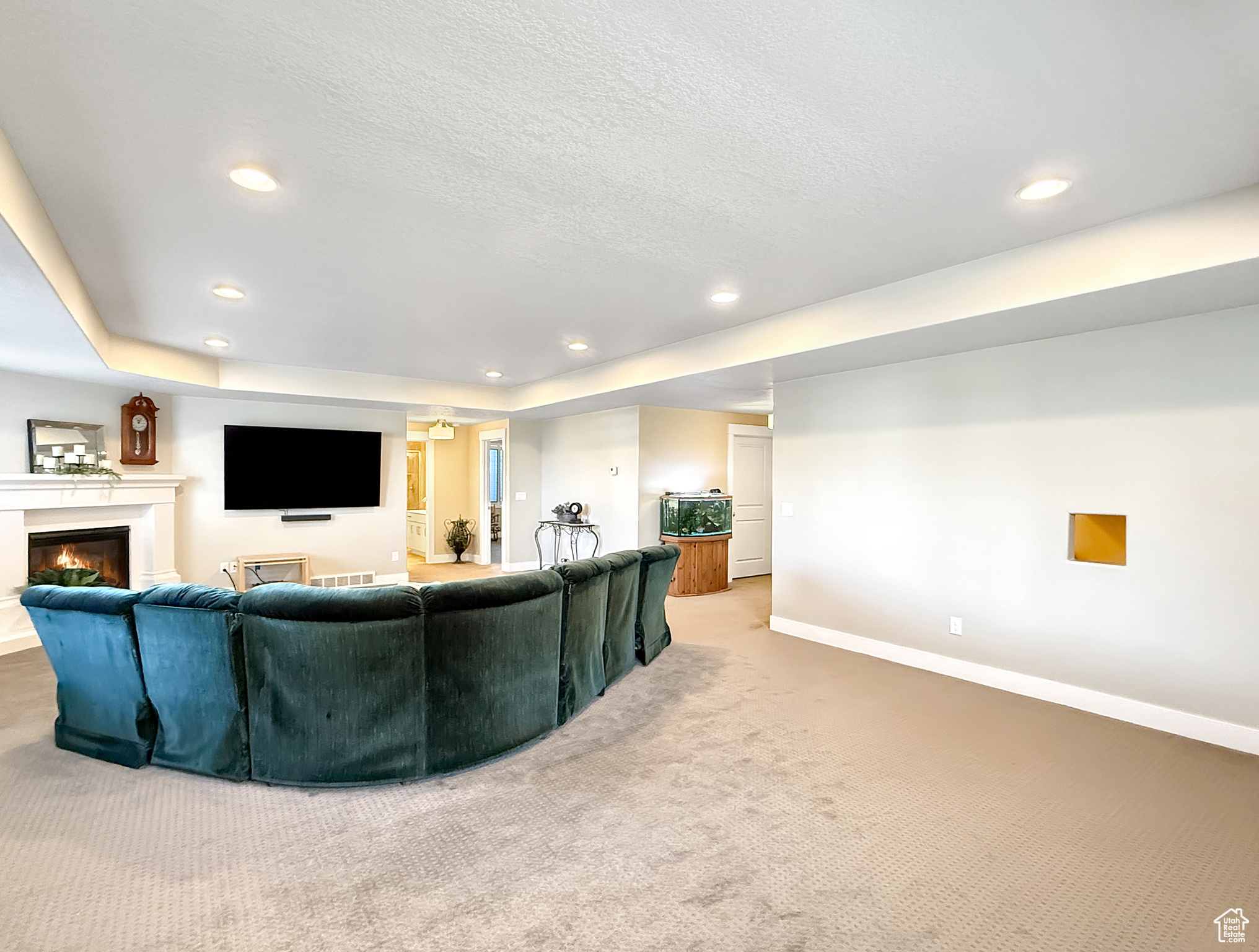 Living room featuring carpet, recessed lighting, a glass covered fireplace, a textured ceiling, and baseboards