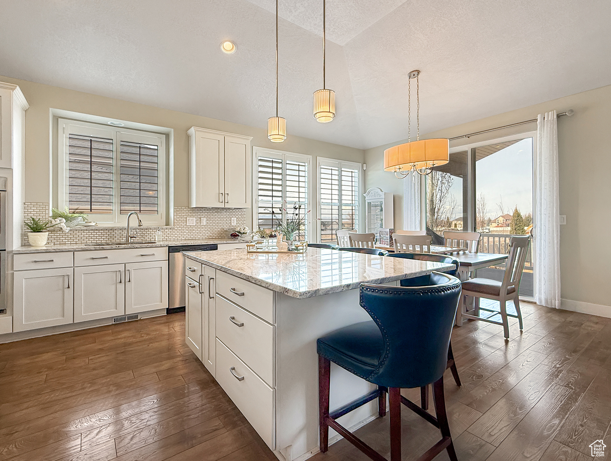 Kitchen with a sink, stainless steel dishwasher, a center island, dark wood-style floors, and tasteful backsplash