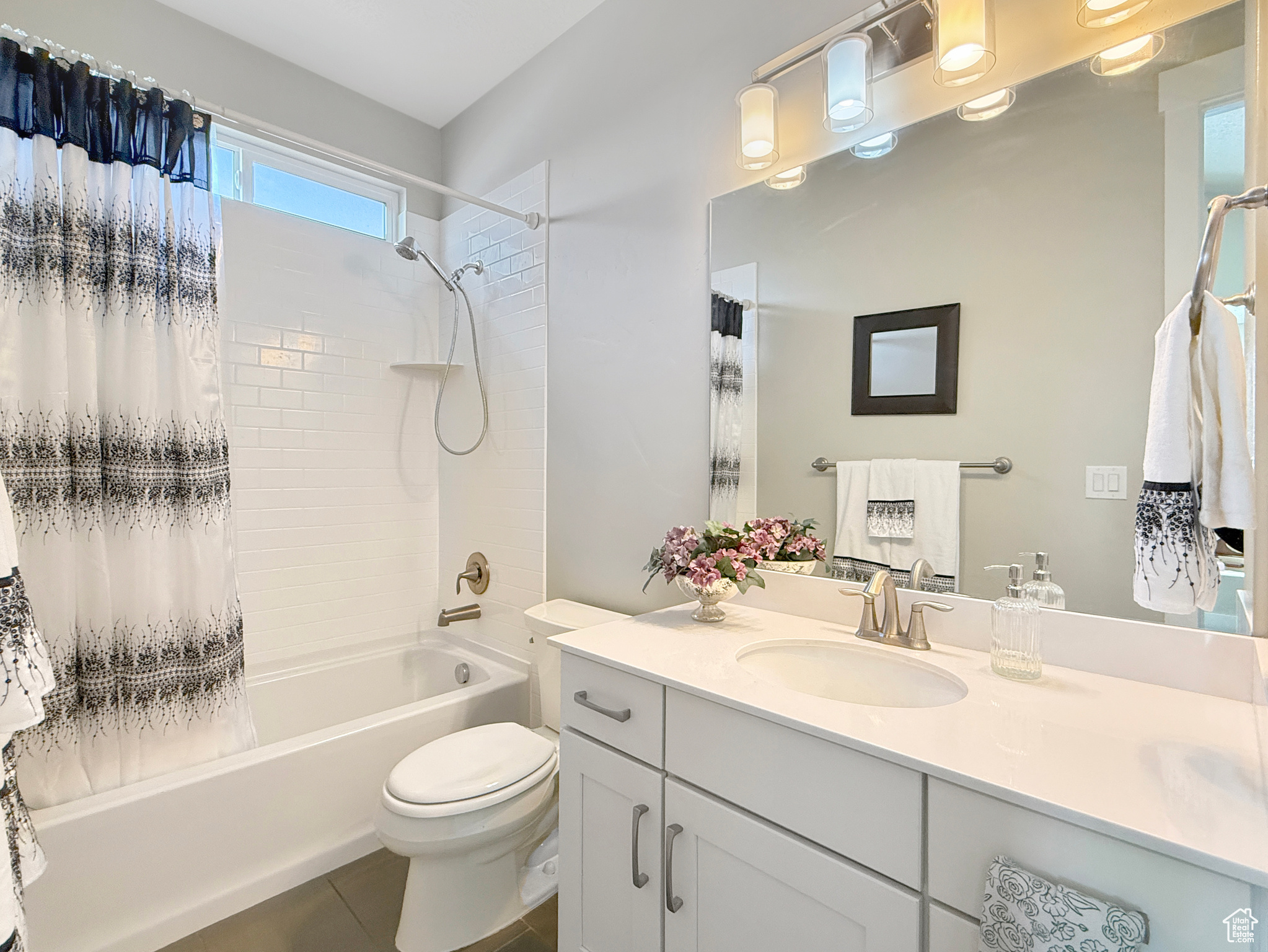 Bathroom featuring toilet, tile patterned floors, shower / bathtub combination with curtain, and vanity