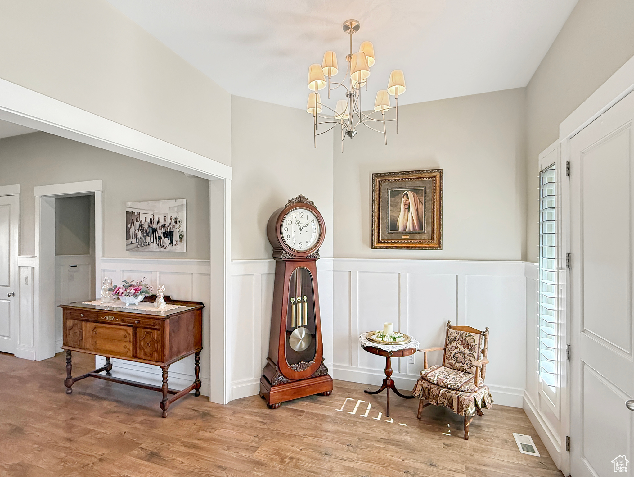 Sitting room with light wood-style floors, a chandelier, visible vents, and wainscoting