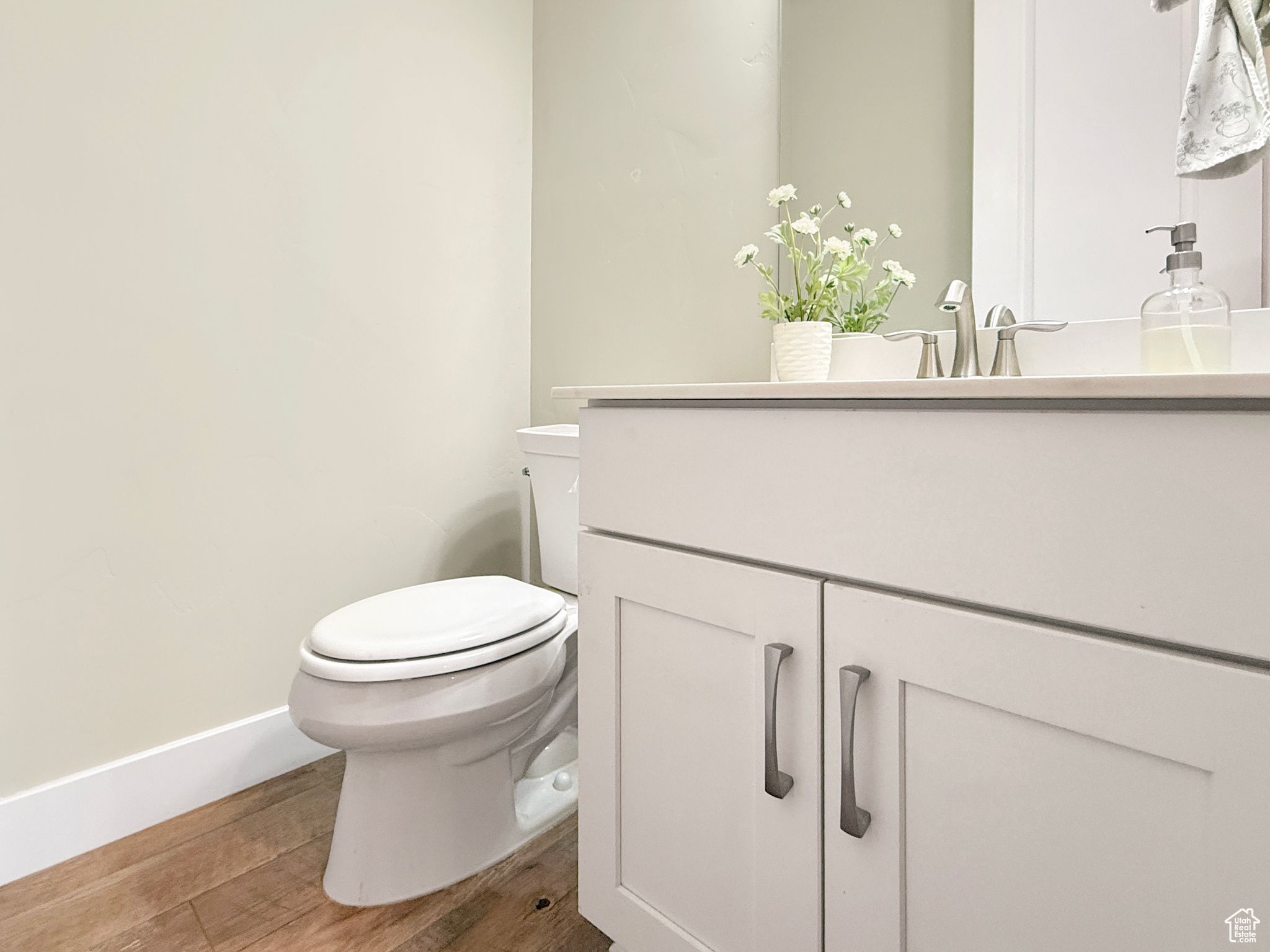 Half bathroom featuring vanity, wood finished floors, toilet, and baseboards