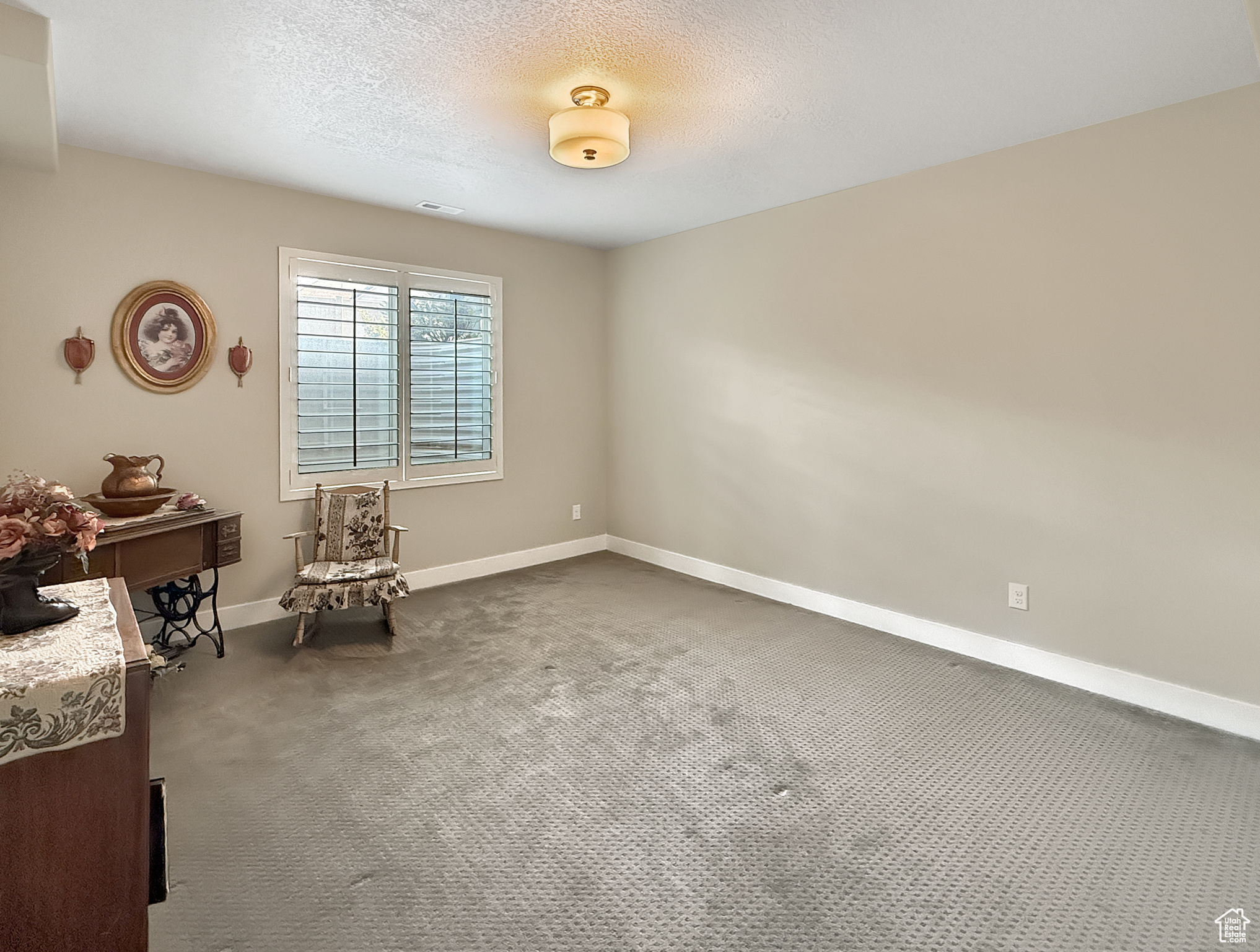 Living area with visible vents, baseboards, dark colored carpet, and a textured ceiling