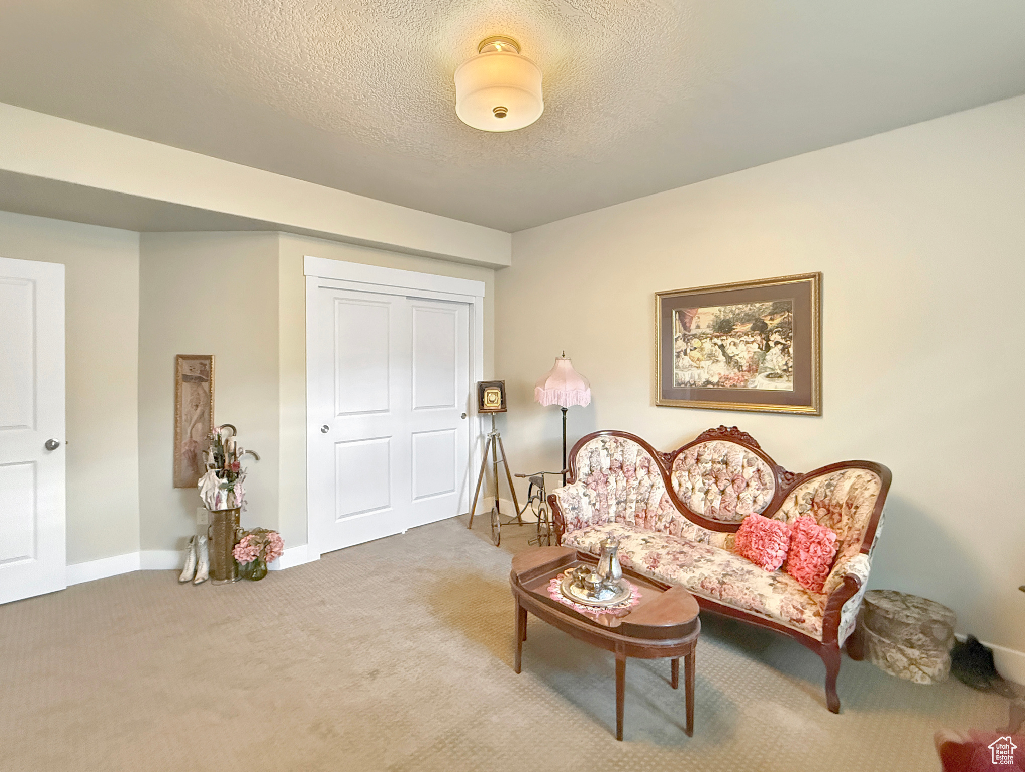 Living area featuring a textured ceiling, carpet flooring, and baseboards