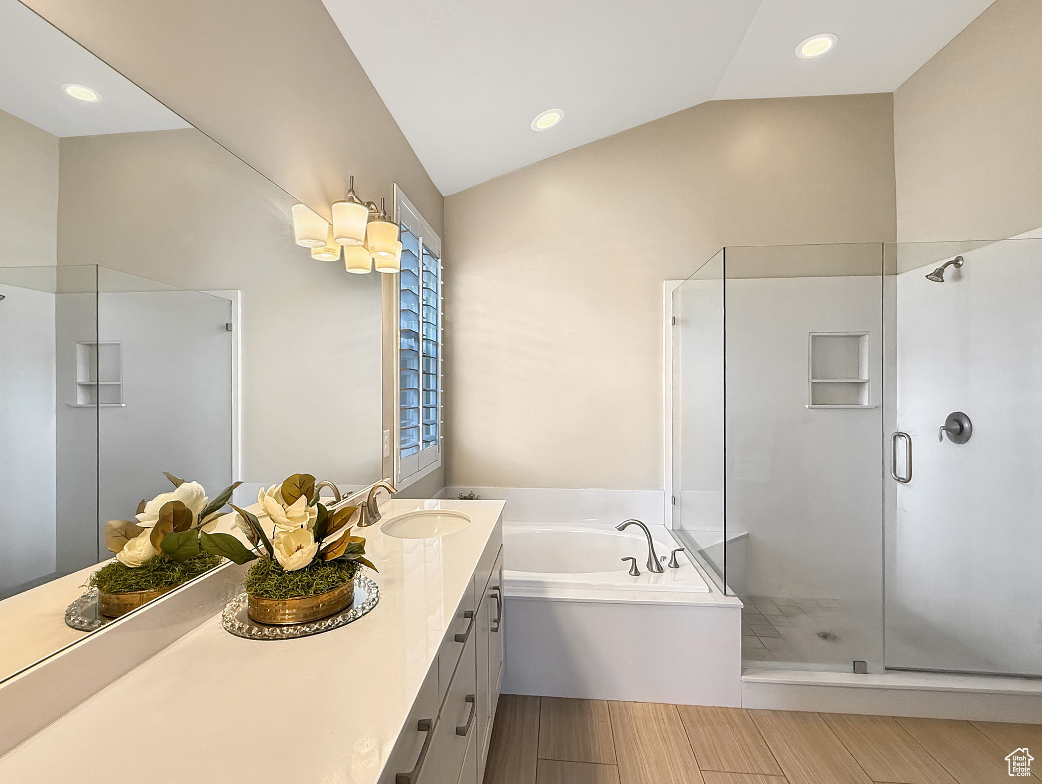 Bathroom featuring wood tiled floor, vaulted ceiling, a shower stall, vanity, and a bath