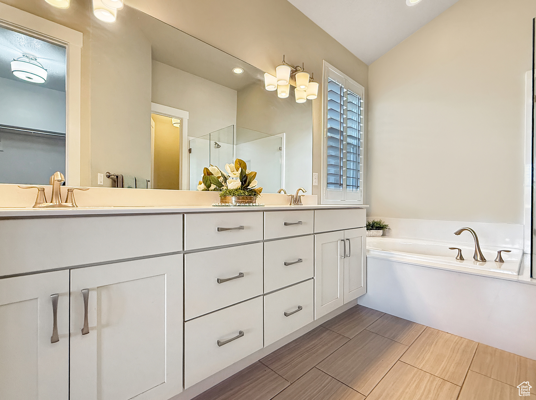 Full bath featuring a garden tub, a sink, vaulted ceiling, double vanity, and a stall shower