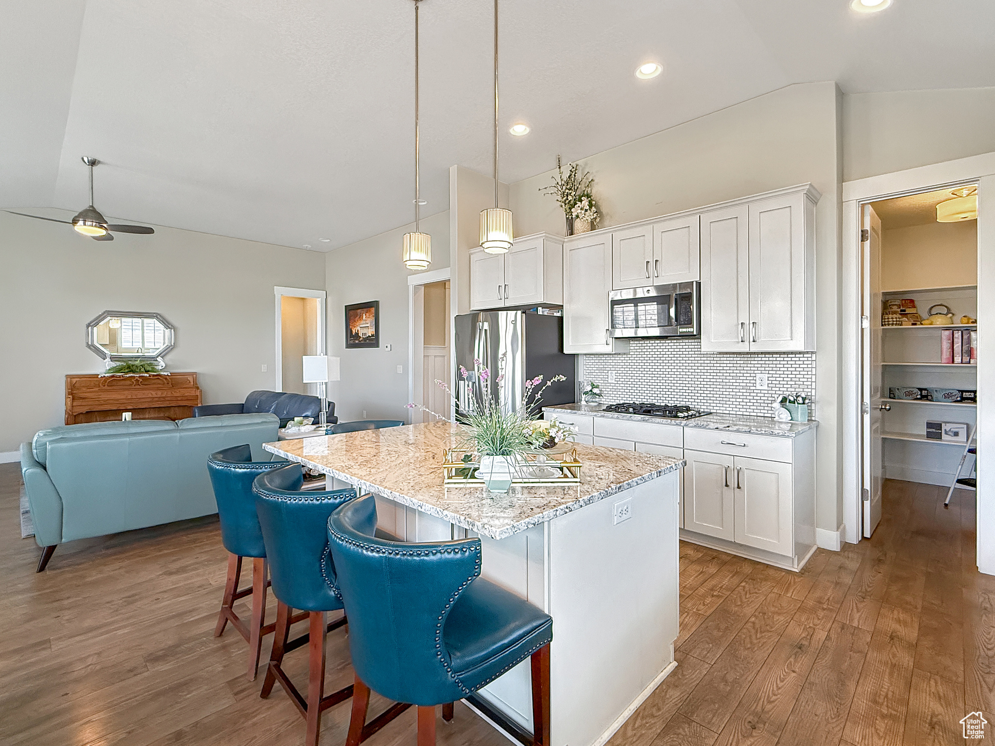 Kitchen with lofted ceiling, stainless steel appliances, a kitchen island, wood finished floors, and white cabinets