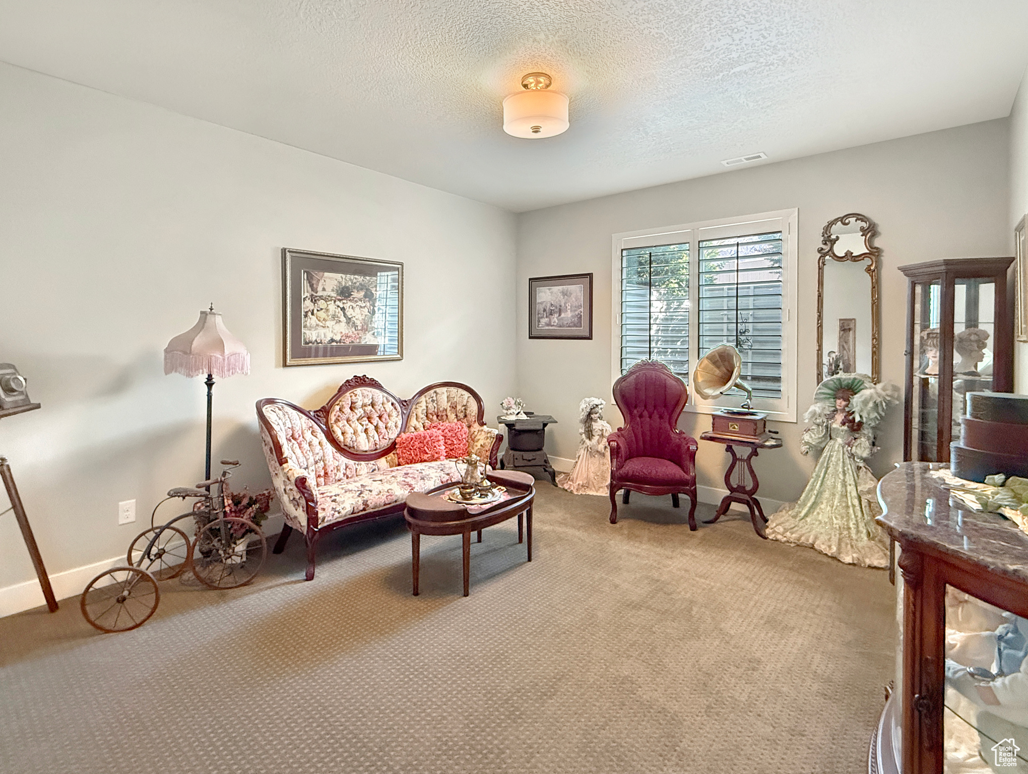 Sitting room with a textured ceiling, carpet flooring, visible vents, and baseboards