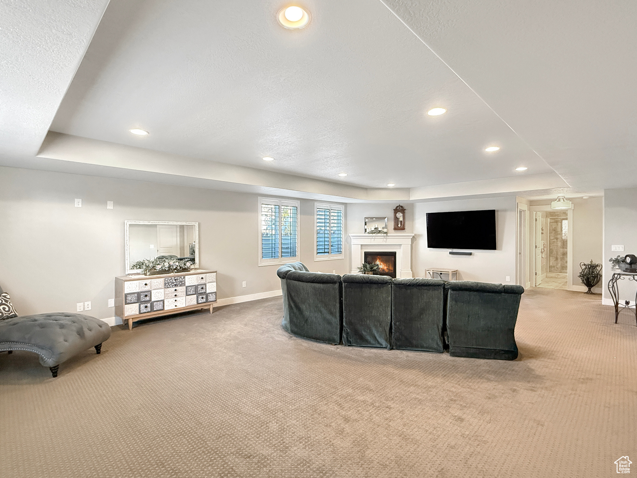 Living room with light carpet, a lit fireplace, recessed lighting, and baseboards