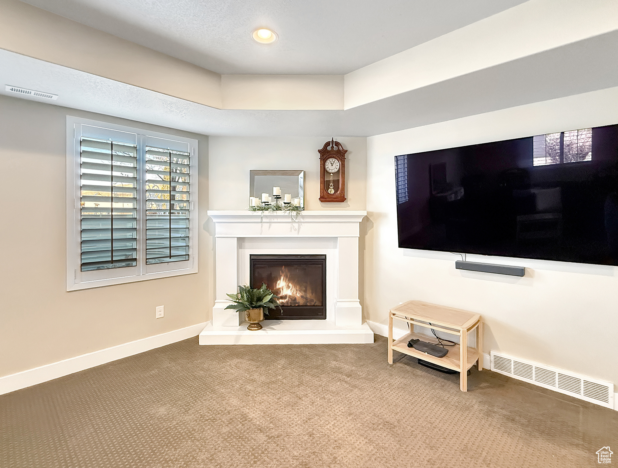 Carpeted living area with recessed lighting, baseboards, visible vents, and a glass covered fireplace