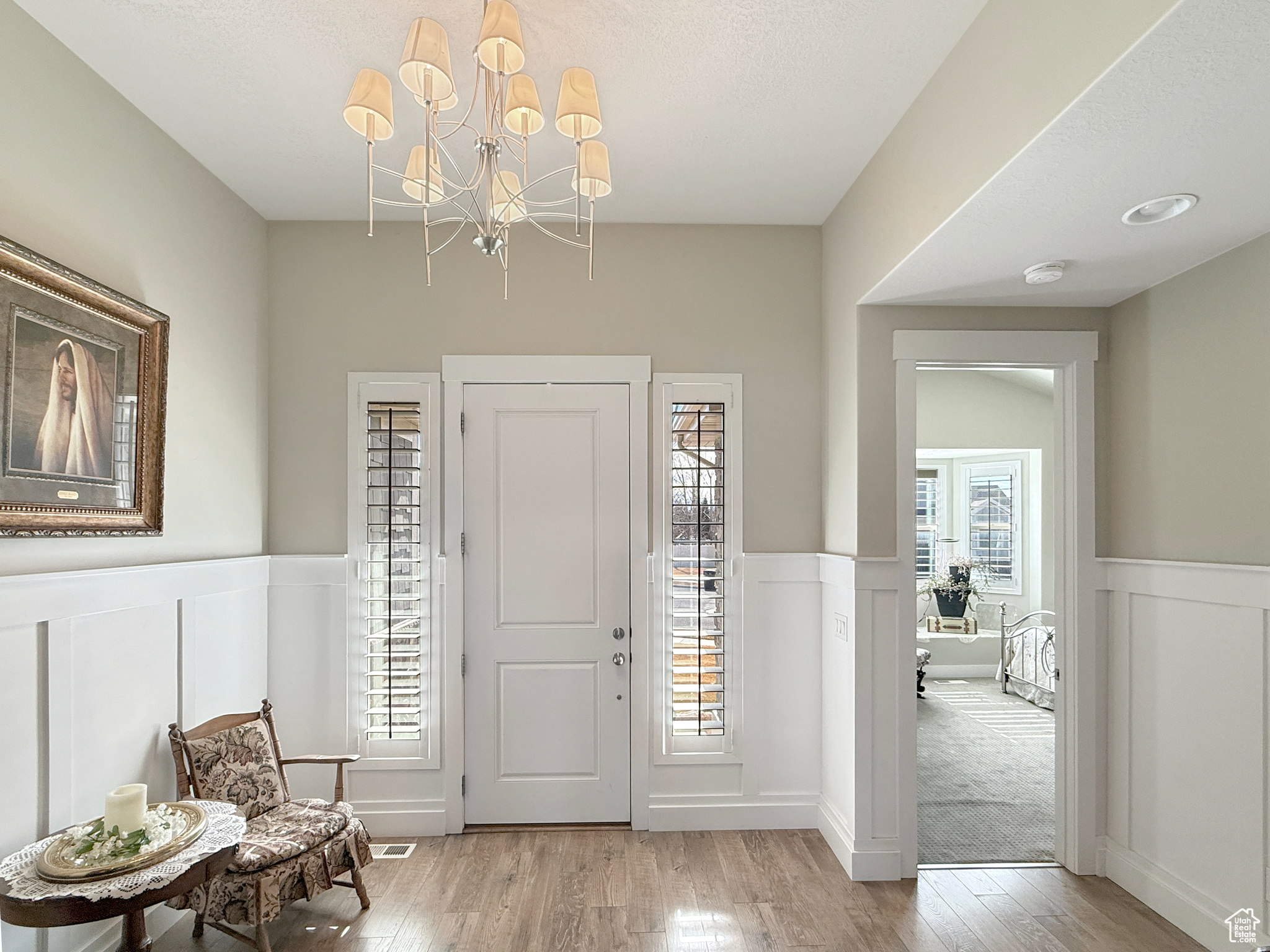 Foyer entrance with wainscoting, light wood-type flooring, and a decorative wall