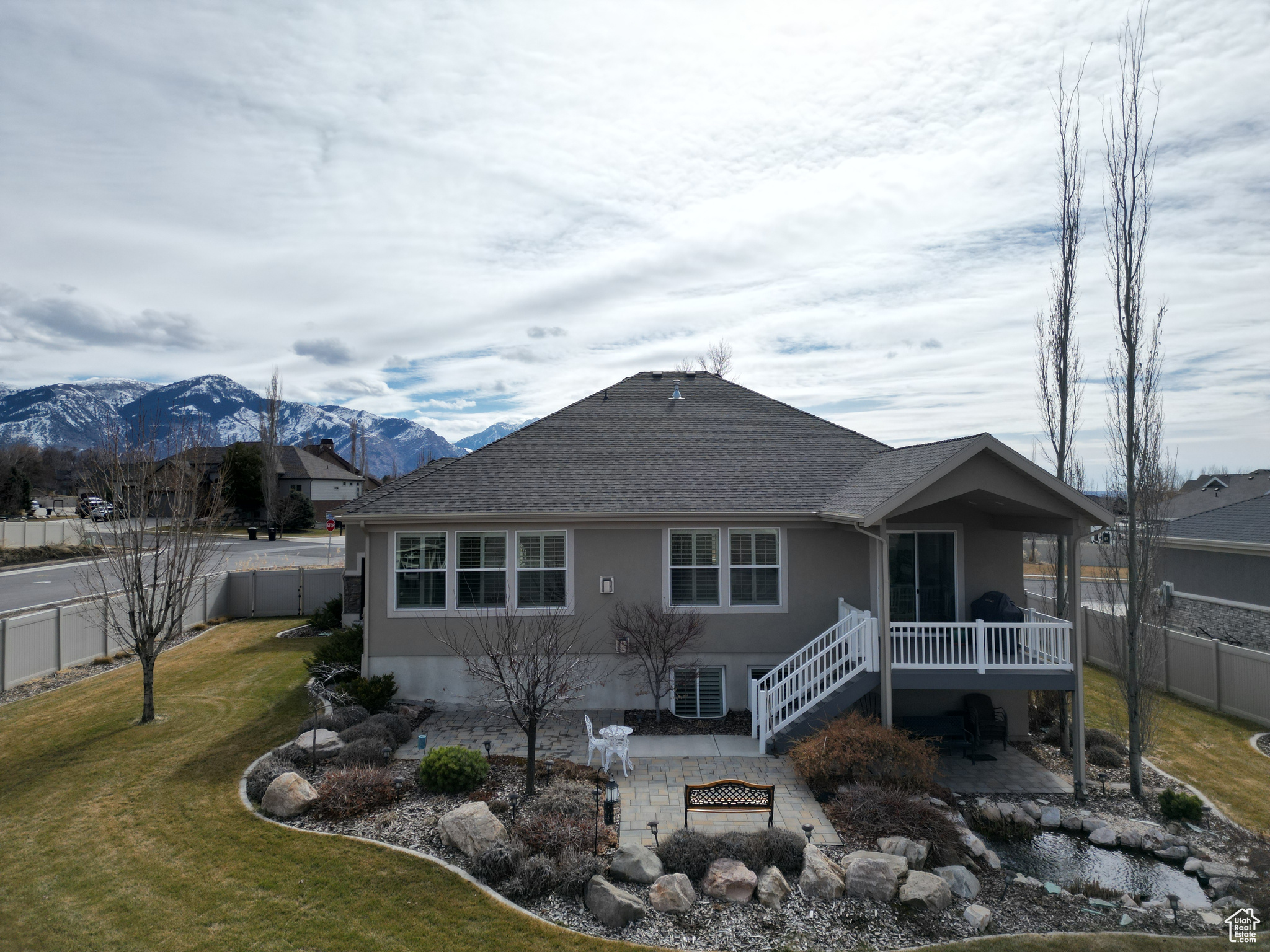 Back of property featuring stucco siding, a fenced backyard, a mountain view, and a patio