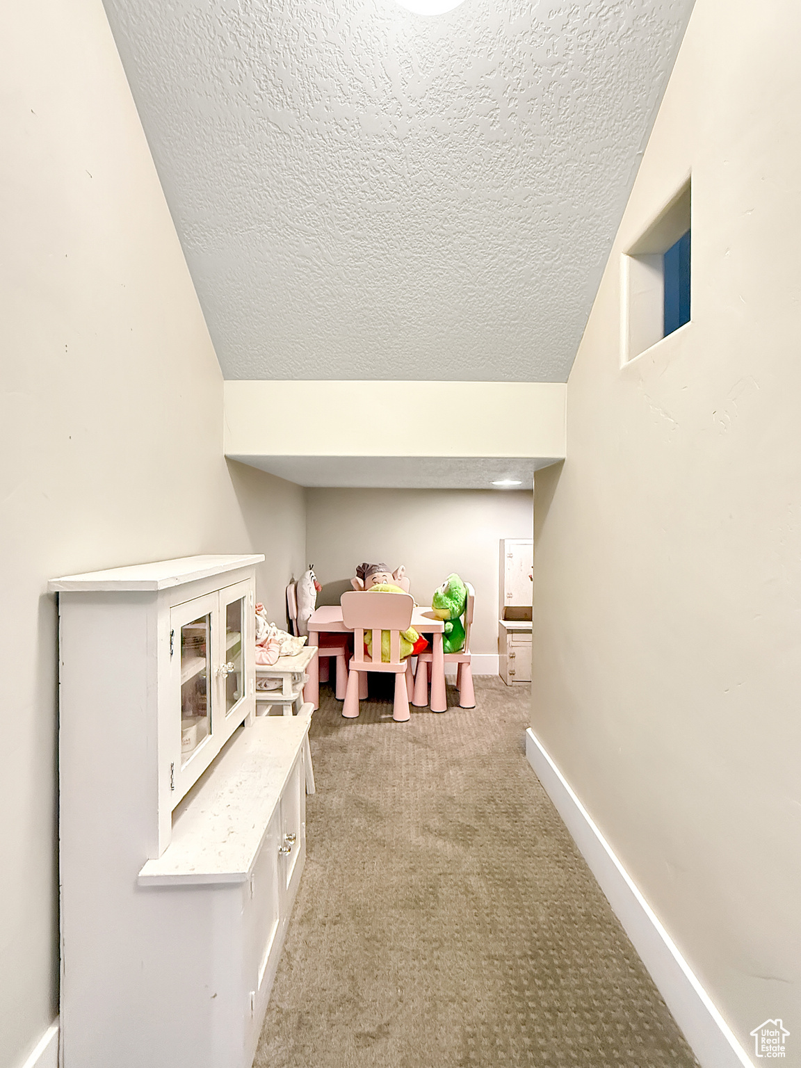 Game room with light carpet, baseboards, vaulted ceiling, and a textured ceiling