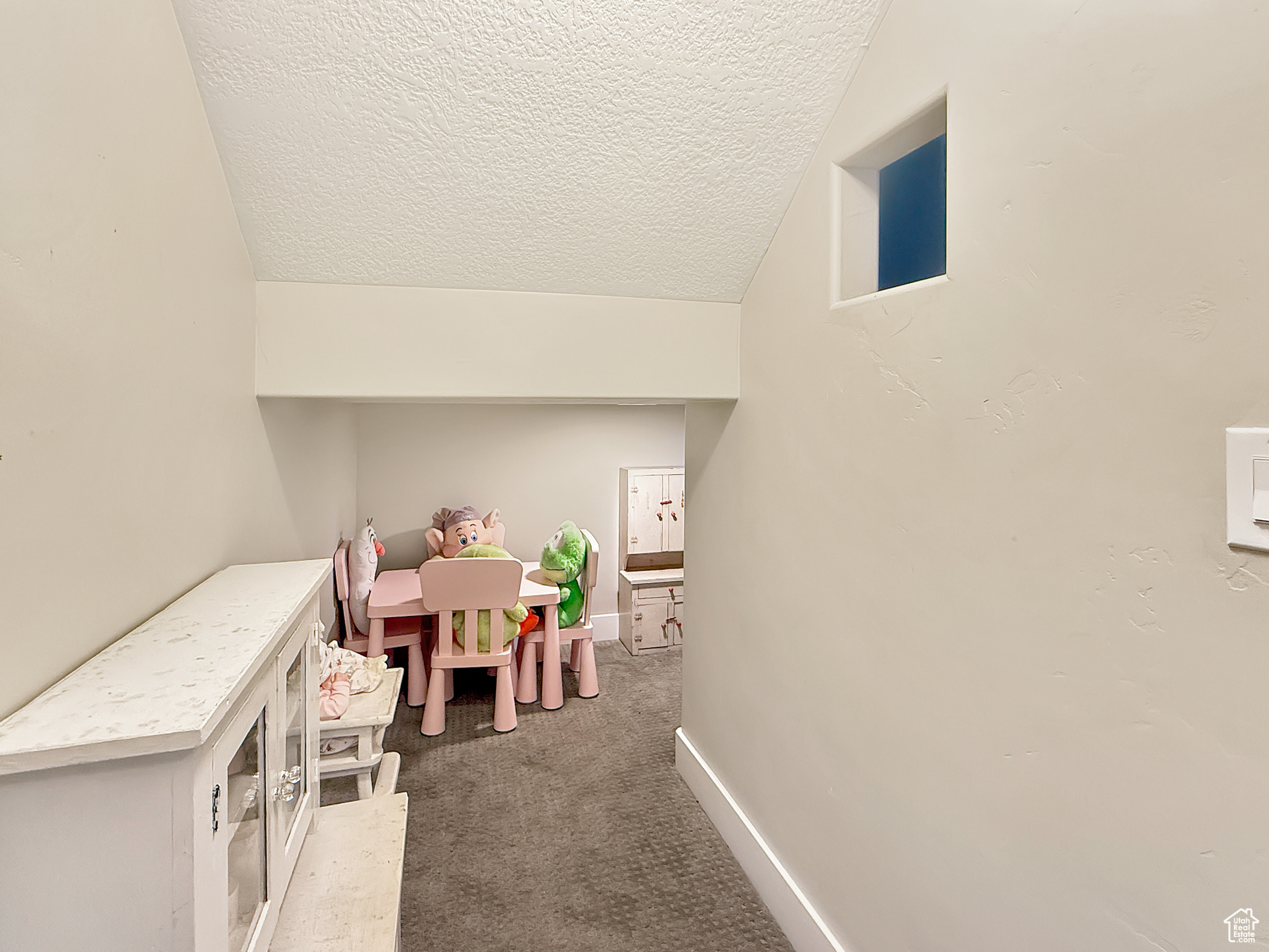 Rec room featuring carpet floors, baseboards, vaulted ceiling, and a textured ceiling