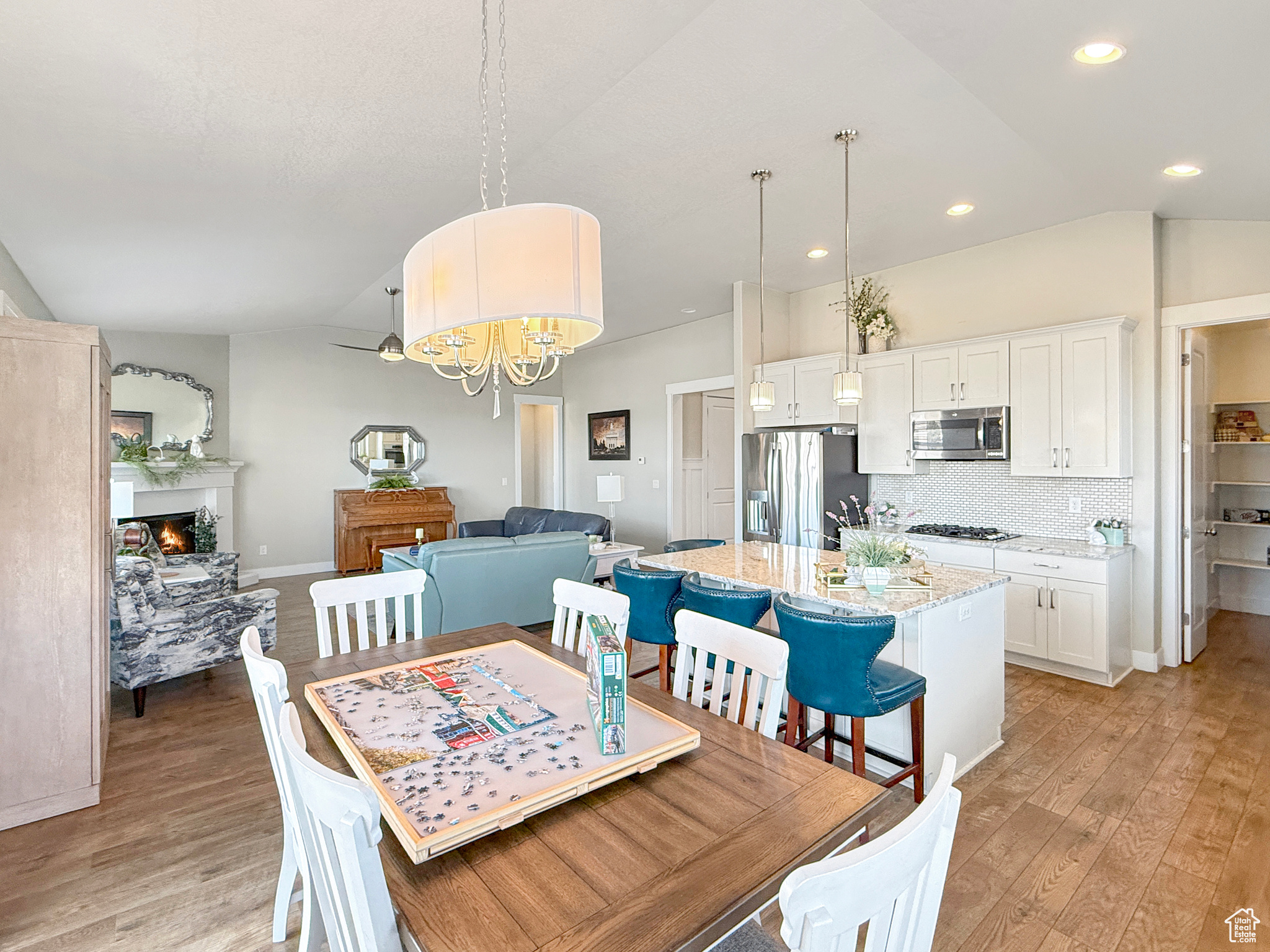 Dining space featuring light wood-style floors, lofted ceiling, a warm lit fireplace, and recessed lighting