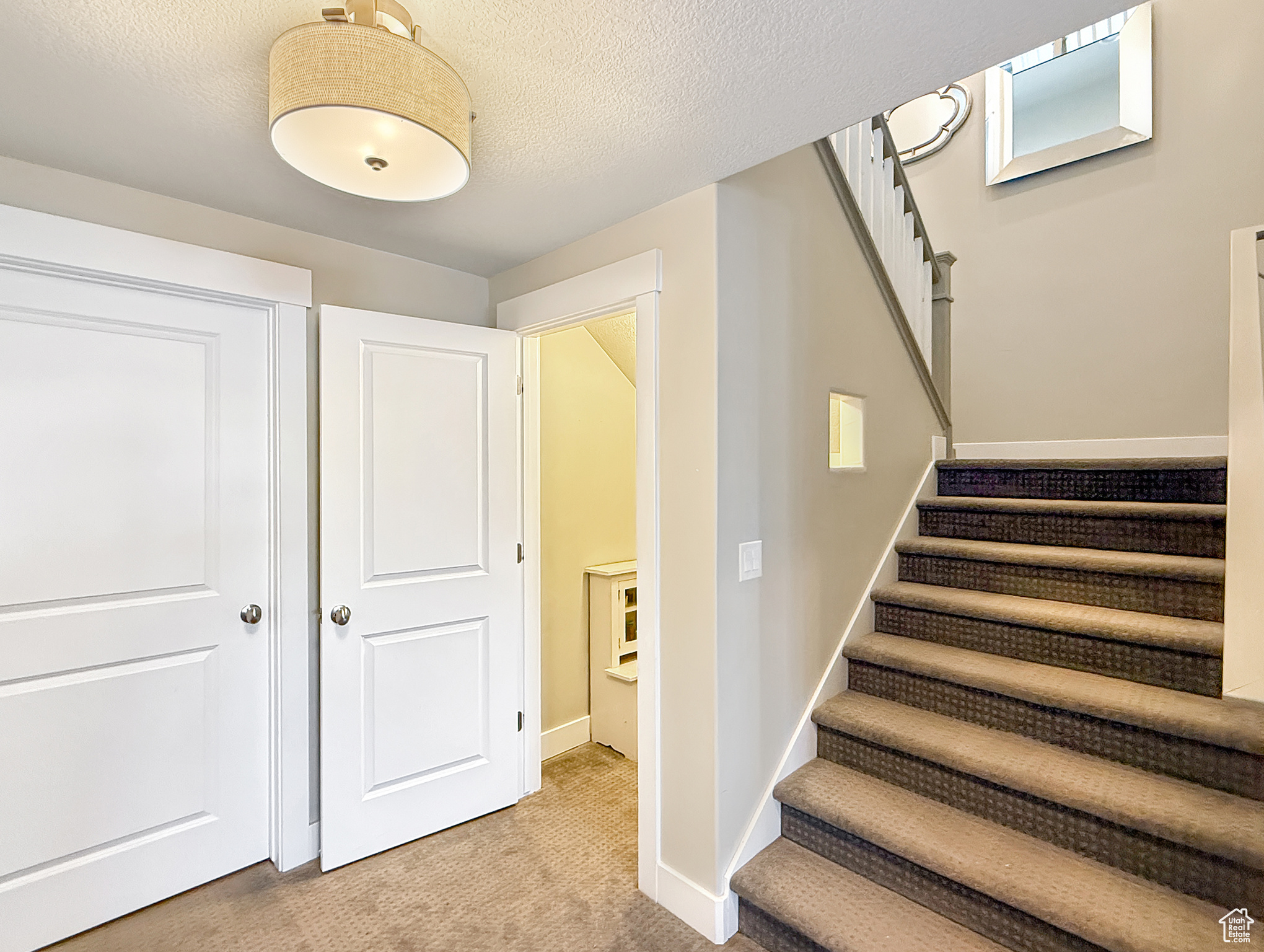 Stairs featuring baseboards, a textured ceiling, and carpet flooring