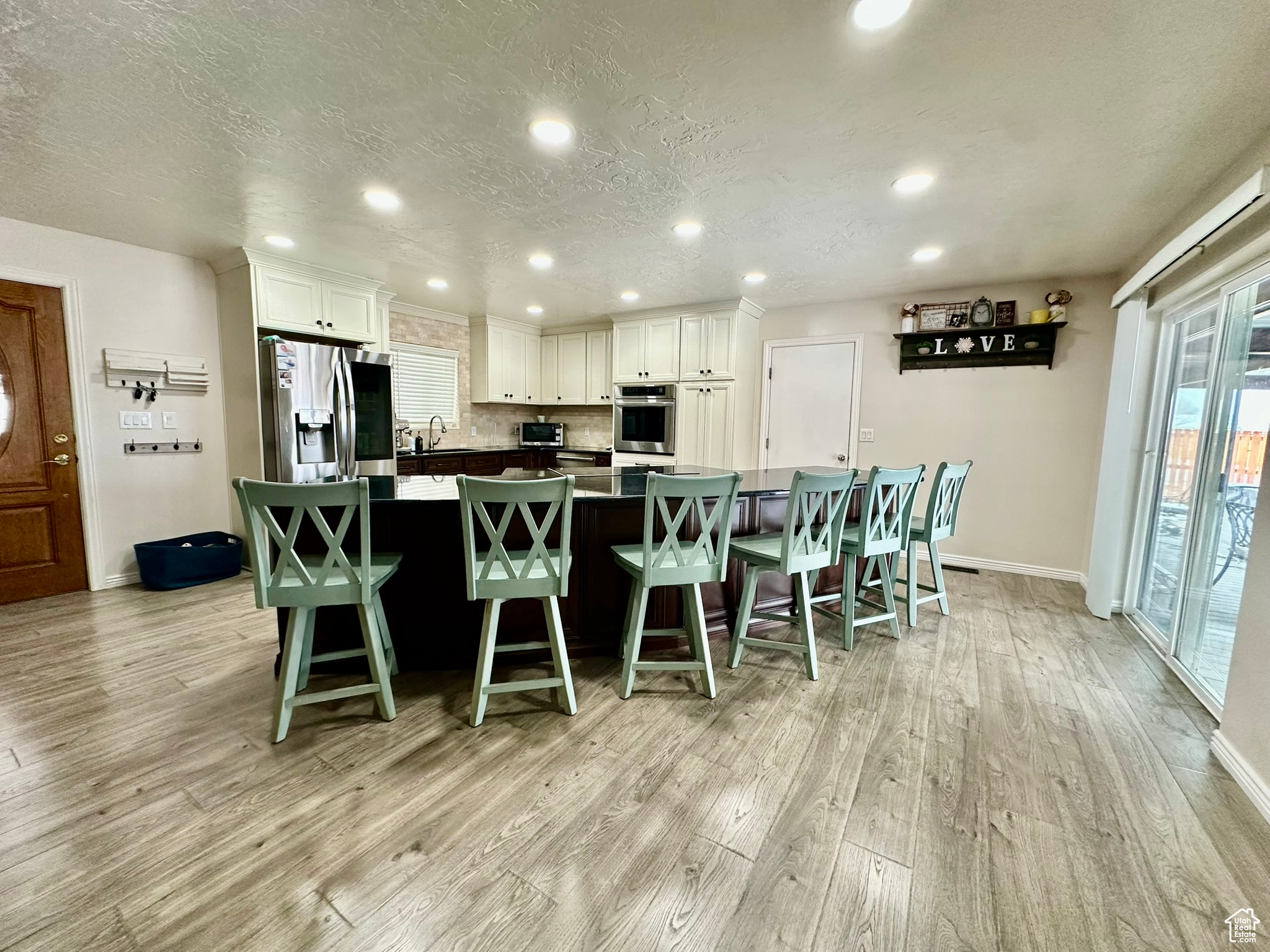 Kitchen with light wood finished floors, a kitchen bar, white cabinetry, and stainless steel refrigerator with ice dispenser